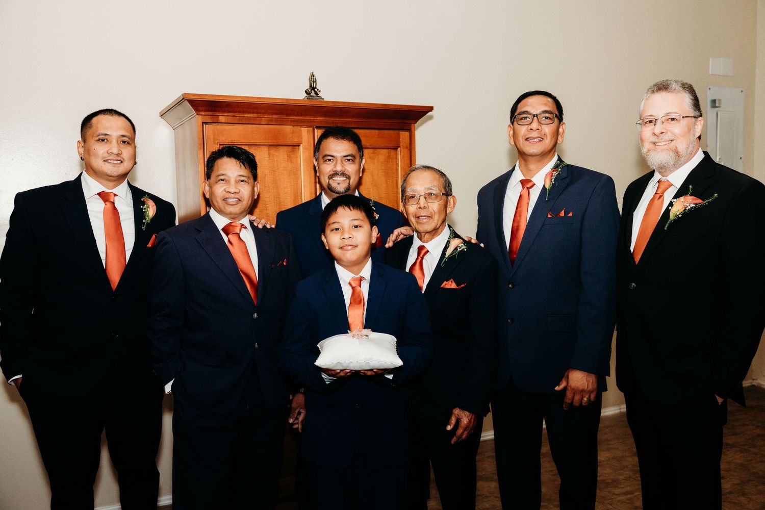 Formal group photo of wedding party members in navy suits and red ties.