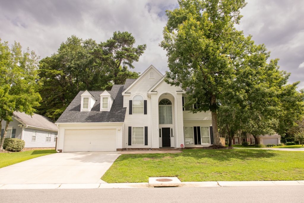 Traditional two-story white house with pillared entrance and attached garage.