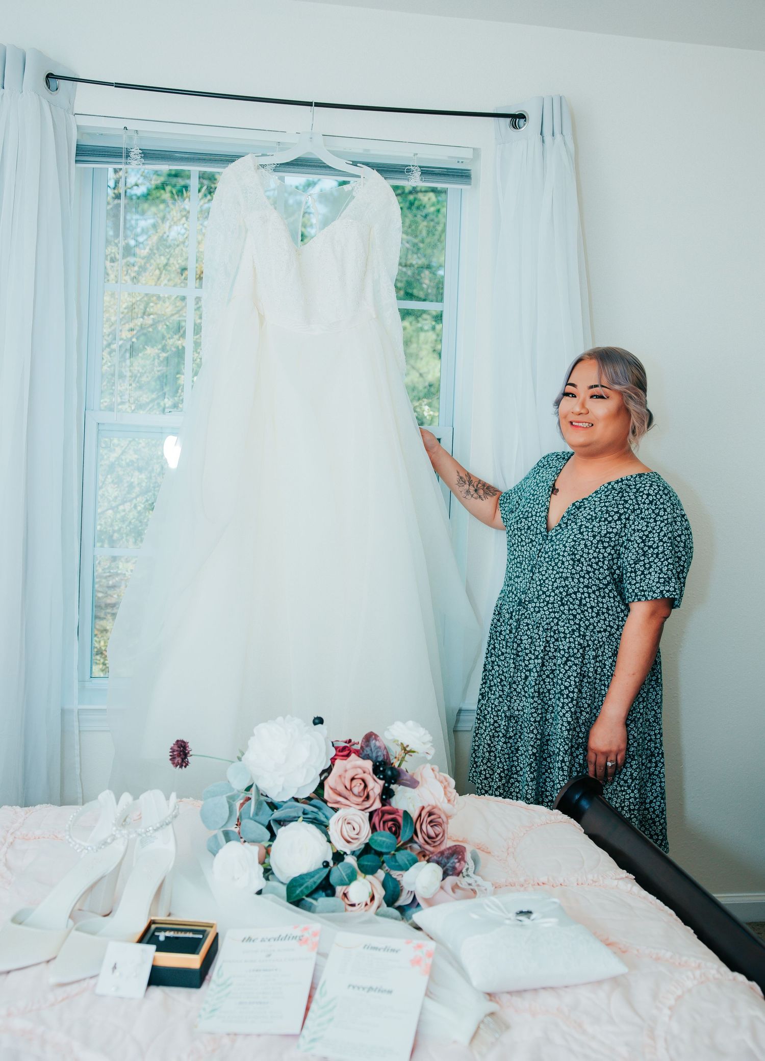 Wedding preparation room with white dresses hanging by the window and floral arrangements.