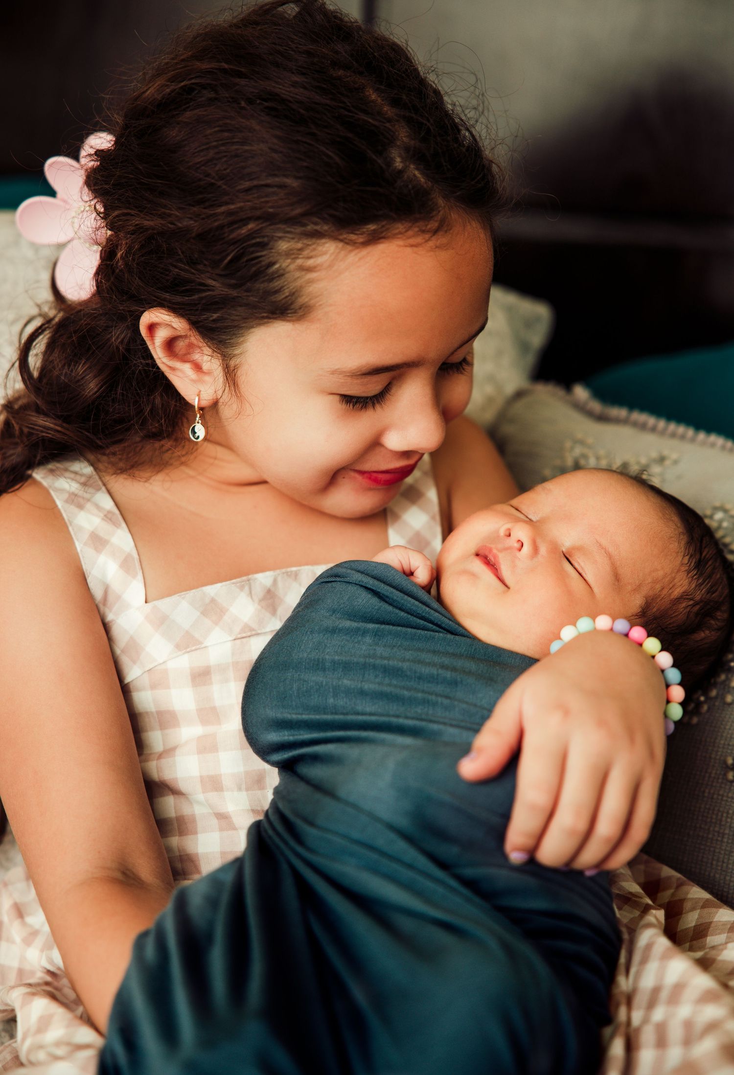 Sweet moment between siblings as older child holds sleeping newborn.