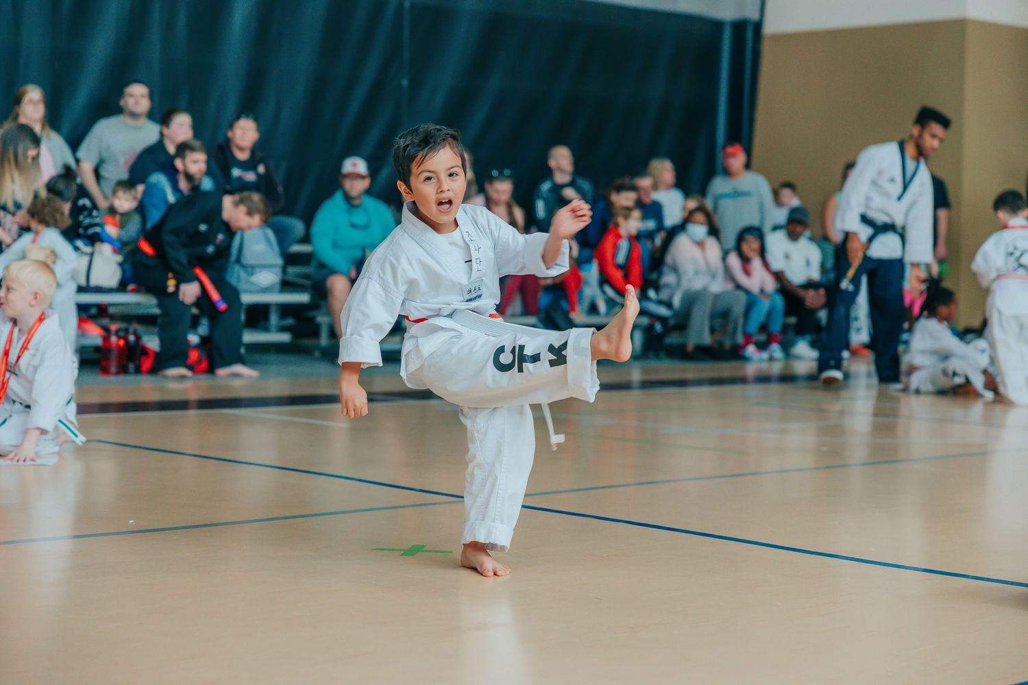 Young athletes practicing martial arts in a bright indoor gymnasium.