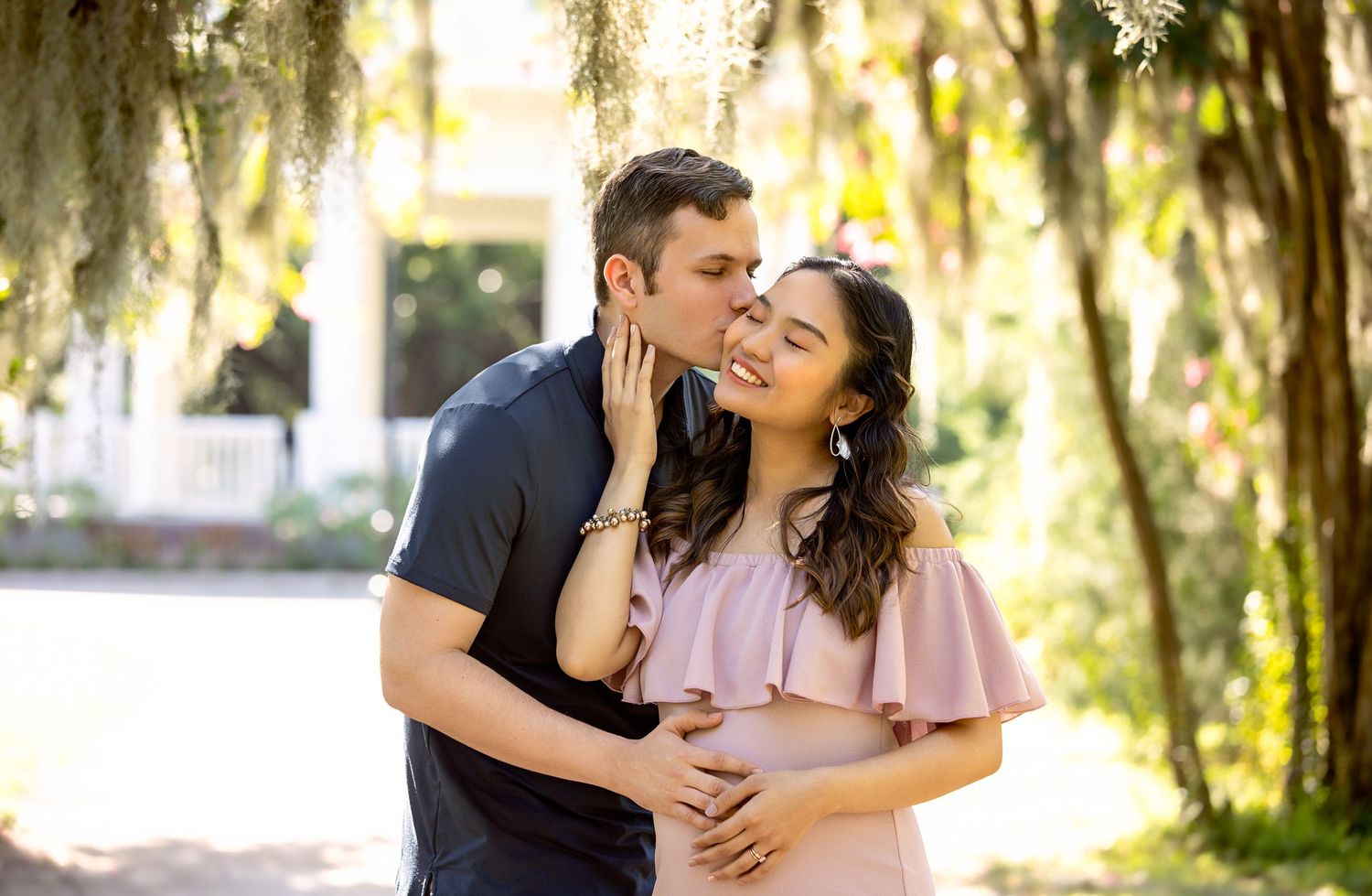 A couple shares affectionate moments under trees draped with Spanish moss.