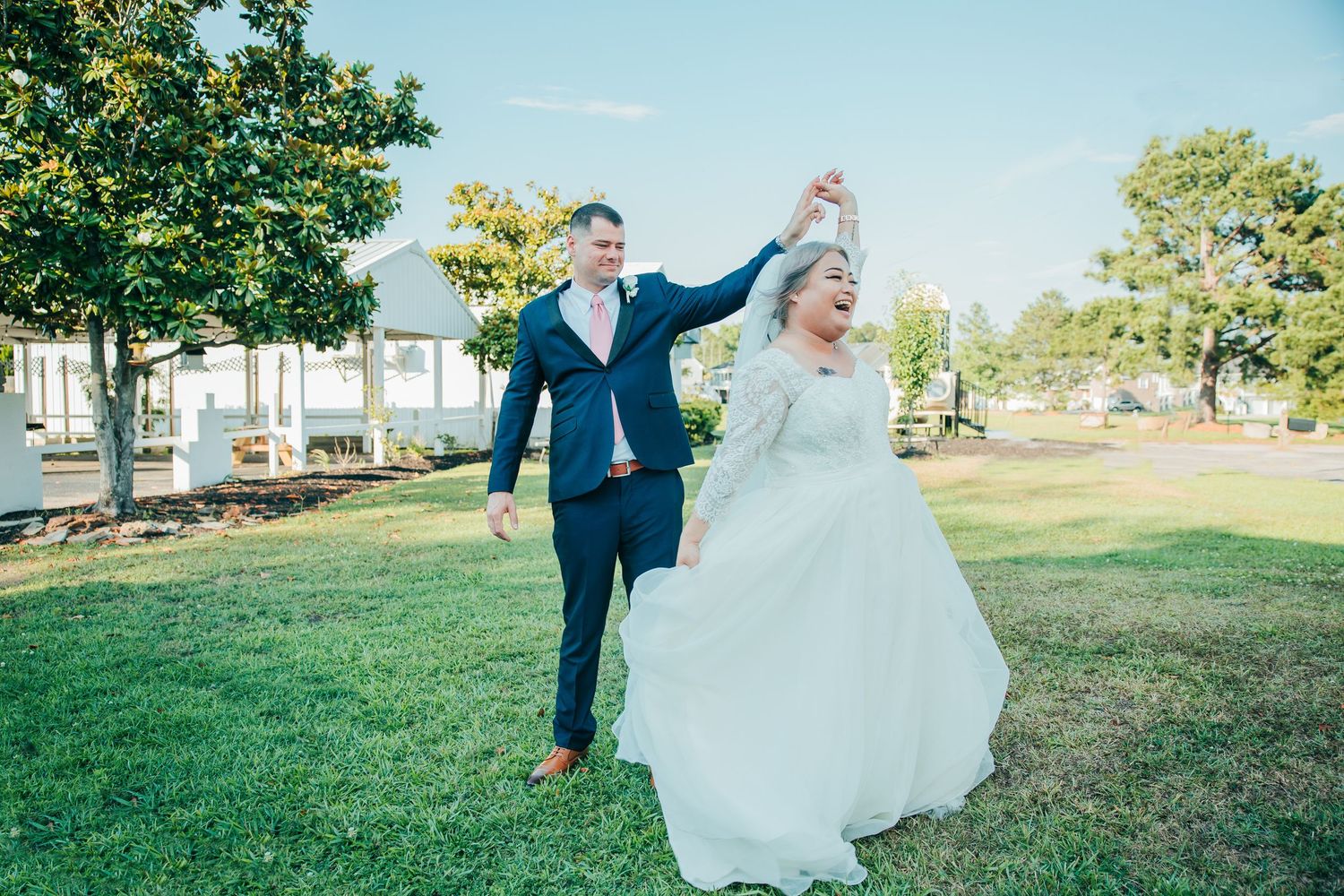 Outdoor wedding photography session on a sunny day with green grass and trees in the background.