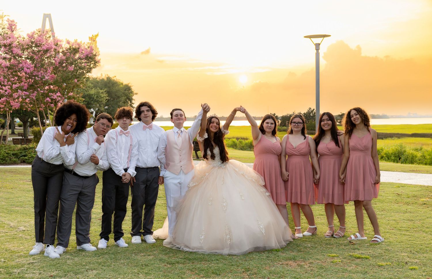 Wedding party poses at sunset in a garden with bridesmaids wearing dusty rose dresses.