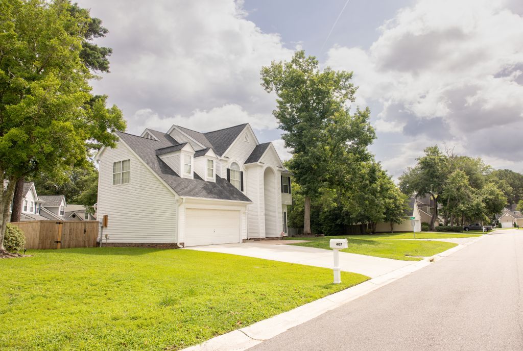 White two-story house with attached garage on quiet residential street.