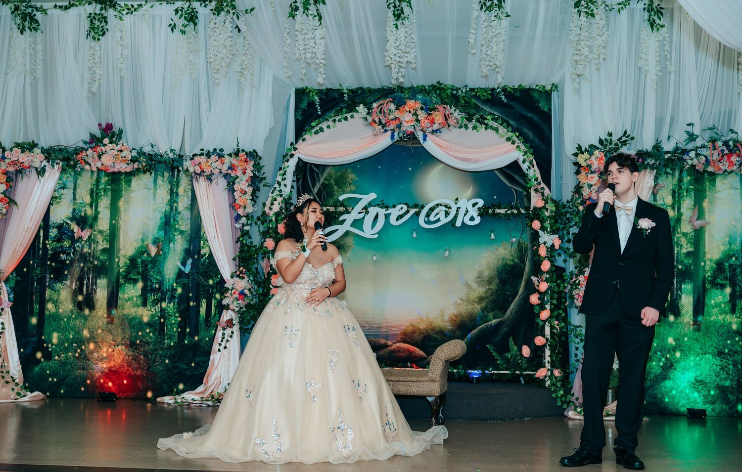 Elegant wedding reception setup with floral arch, draping, and romantic lighting.