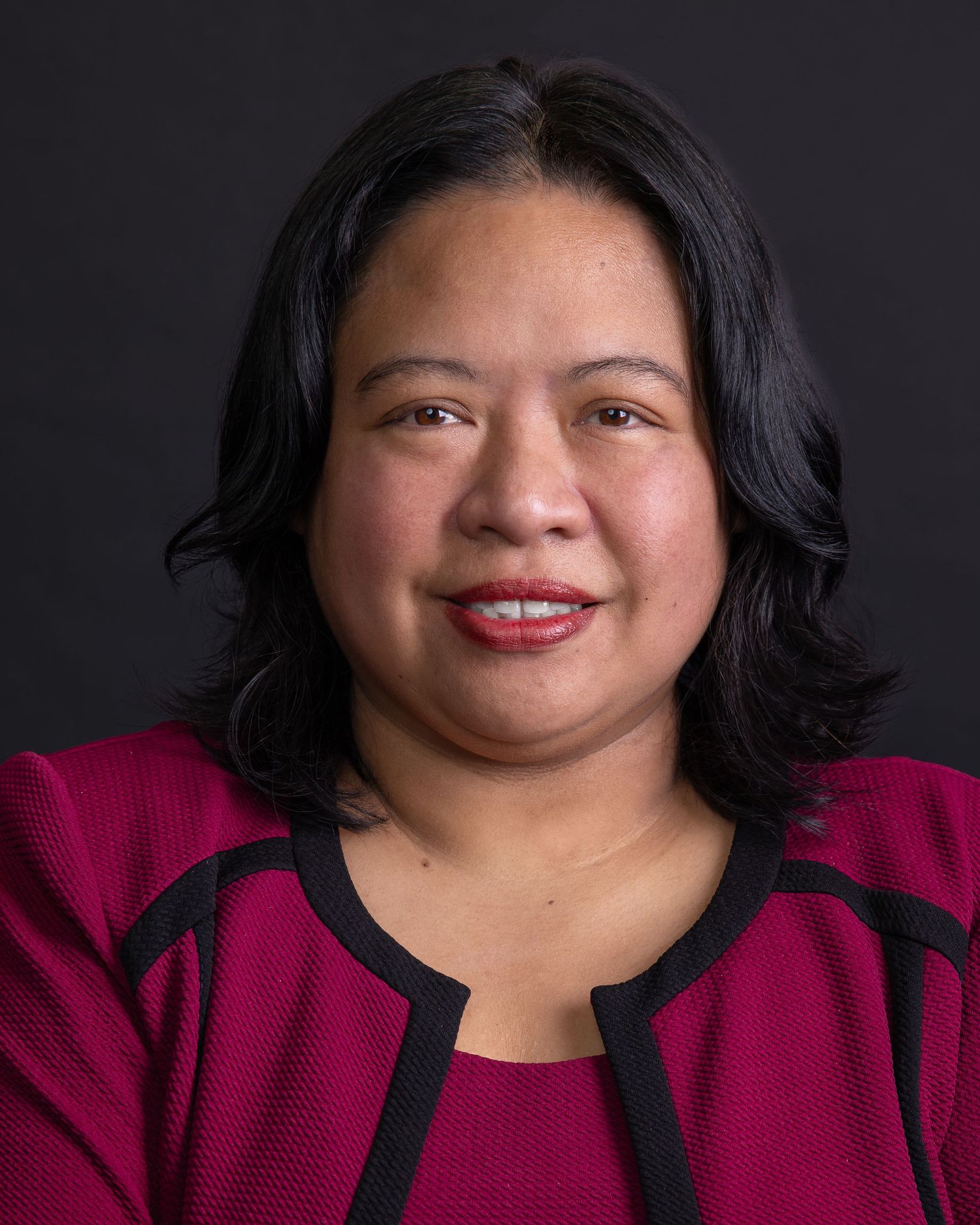 Professional headshots with dark background showcasing warm expressions and magenta outfit.