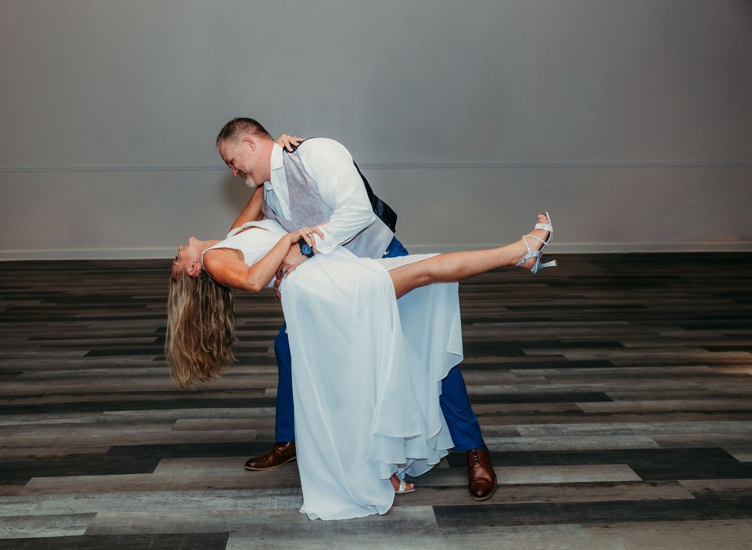 Romantic wedding couple dancing and dipping on wooden floor.
