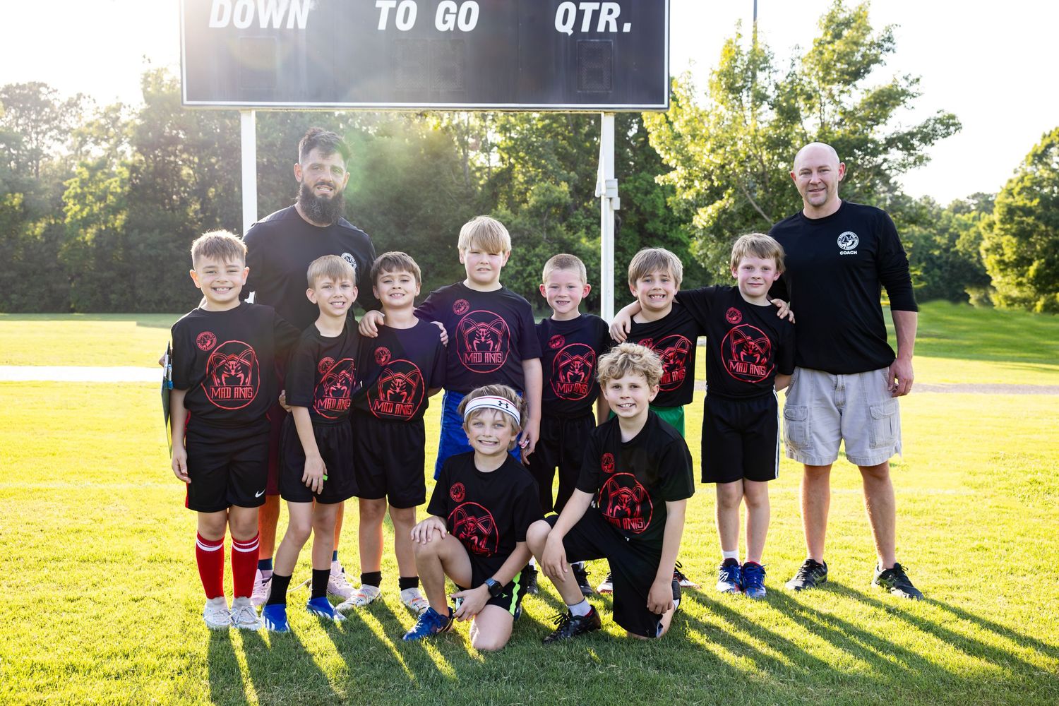 Youth soccer team in black uniforms lined up for a team photo on the field.