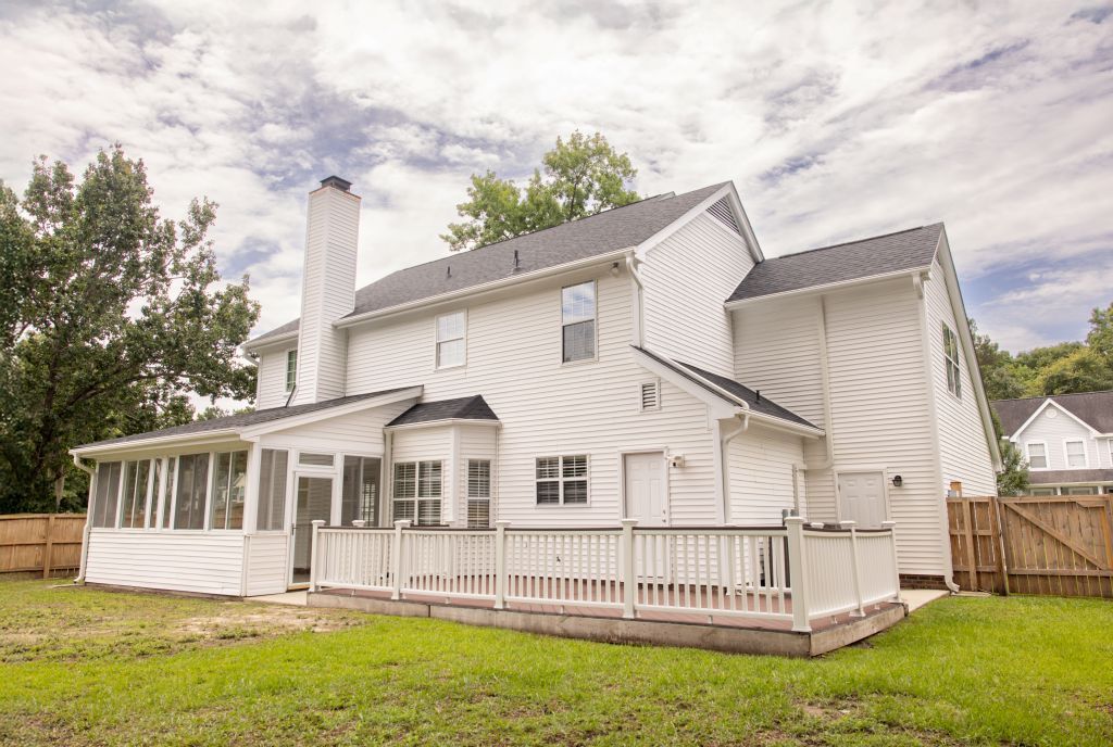 Rear view of large white house with covered porch and wooden deck.