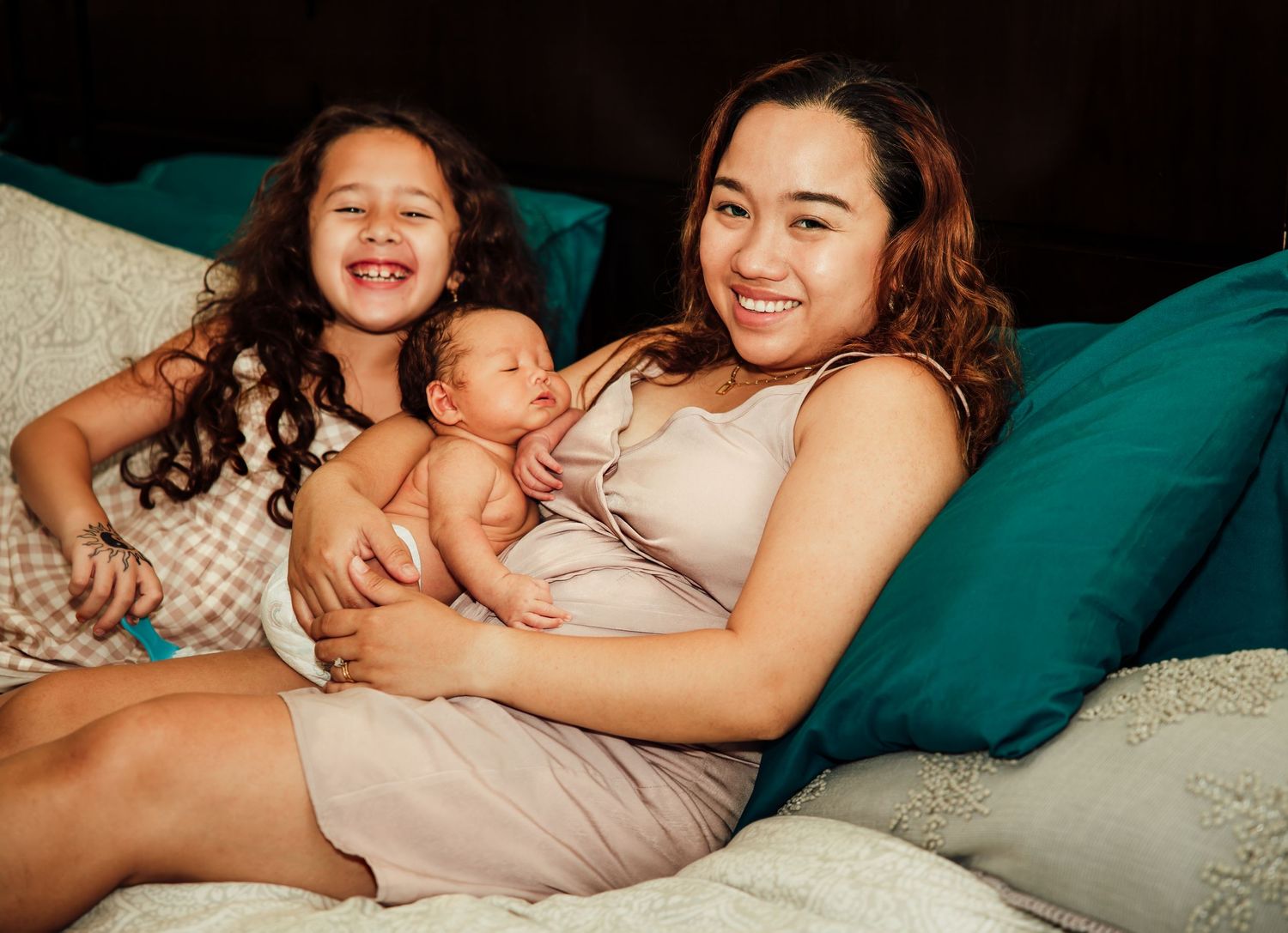Joyful moment shared between family members with a newborn baby on teal cushions.