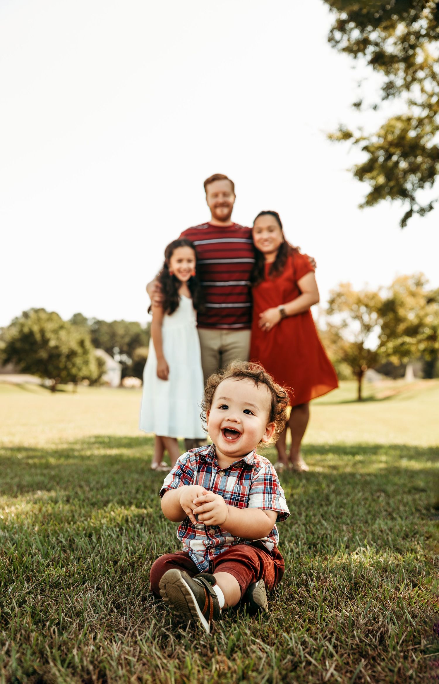 Joyful family moment captured on grass with children laughing in foreground.