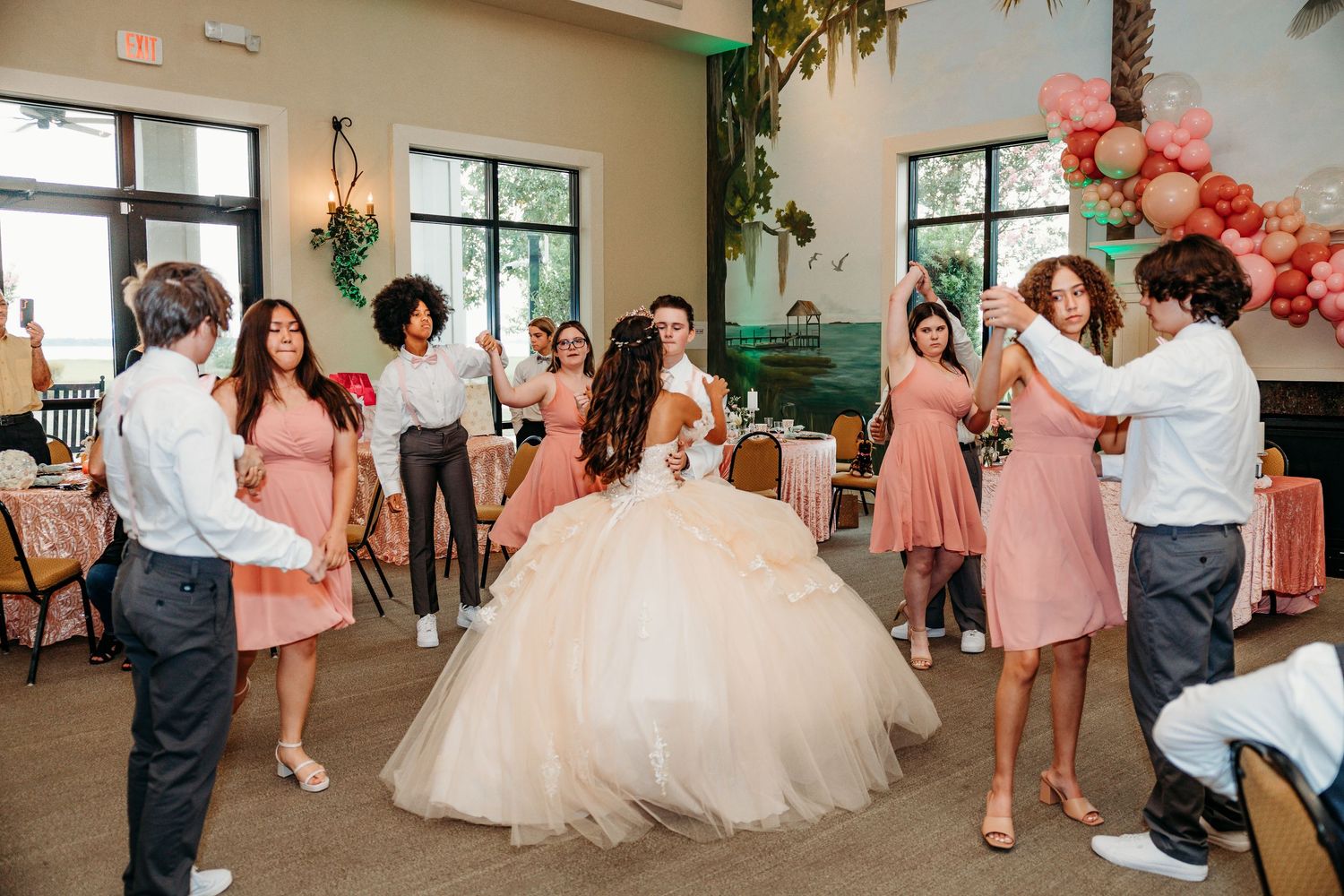 Wedding celebration in an indoor venue with balloon decorations and dancing guests.