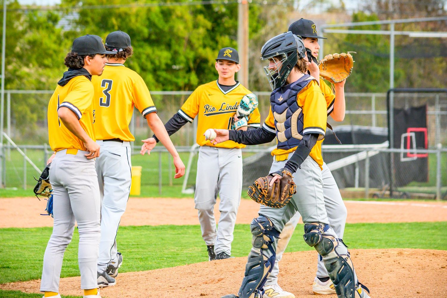 Baseball players in yellow uniforms discussing plays on the field.