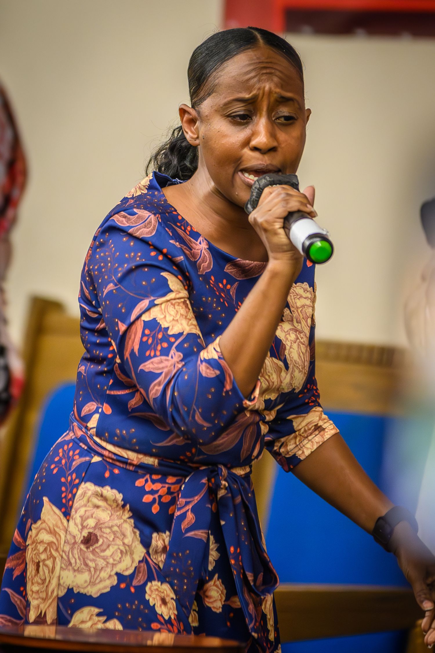 Singer performs in blue floral dress during church service.