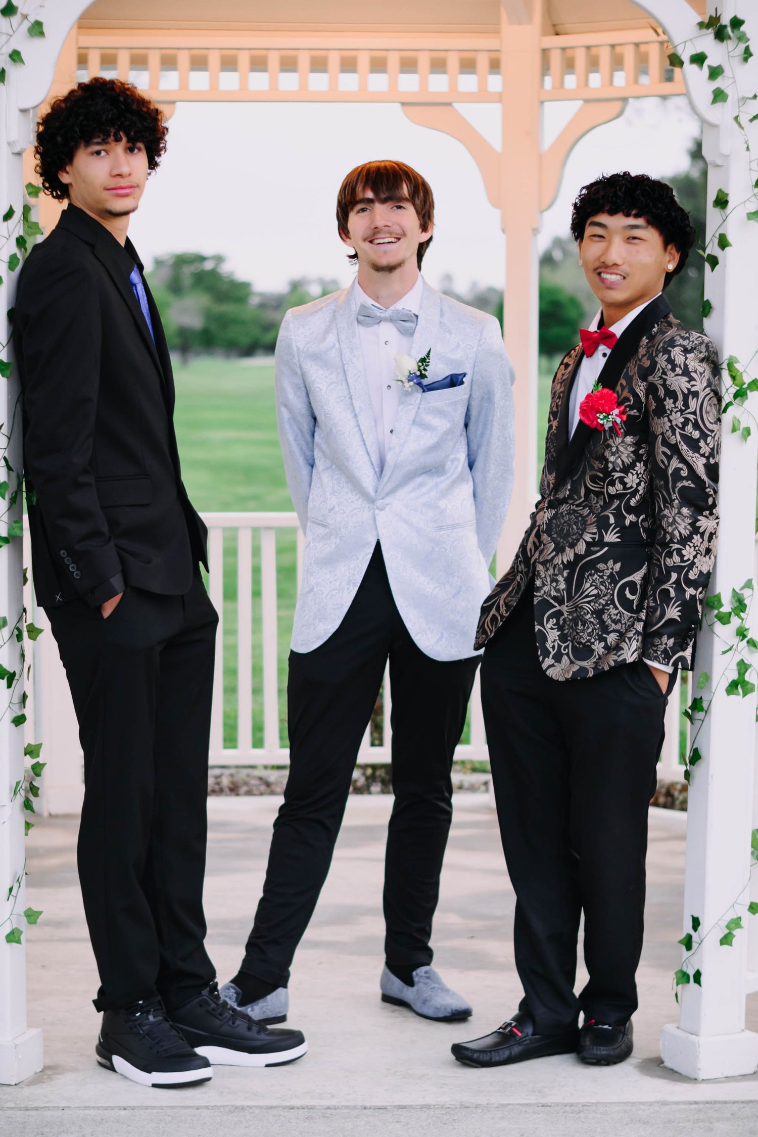 Formal group photo showing people in black suits and white dress shirts standing in front of a decorated outdoor gazebo.