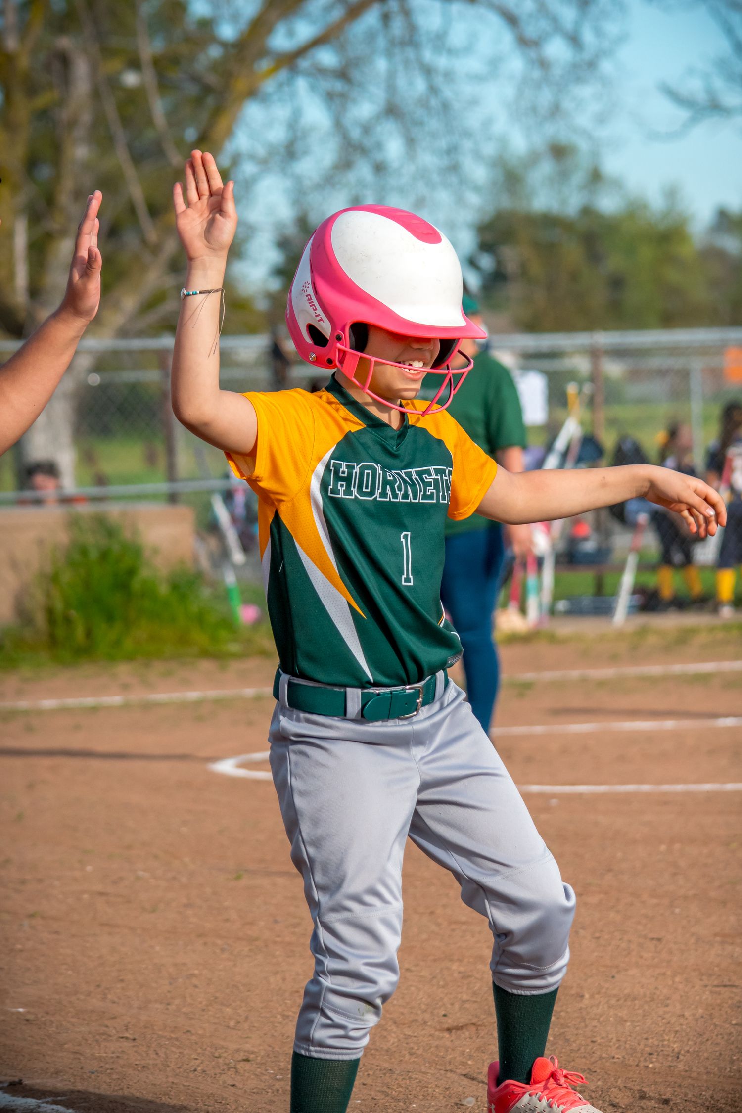 Softball player in green jersey and gray pants demonstrating various running stances on field.