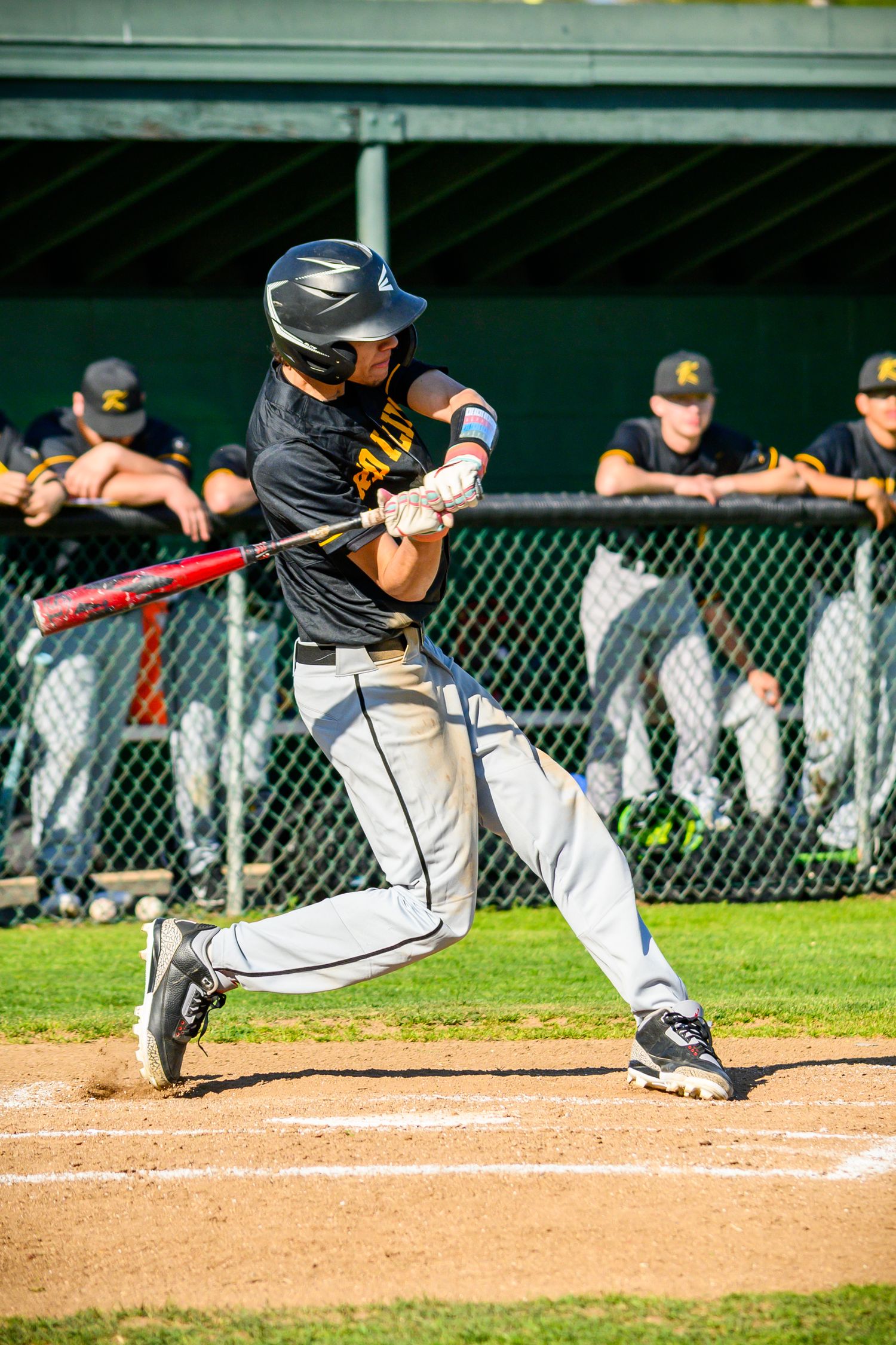 Baseball player executing a bunting technique during a game, demonstrating proper form at home plate.