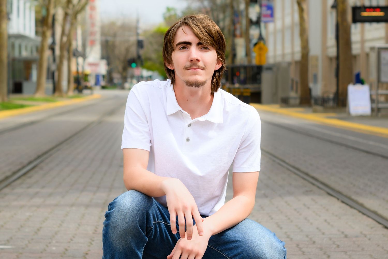 Person with brown hair standing against urban wall backdrop, shown in a series of casual poses.