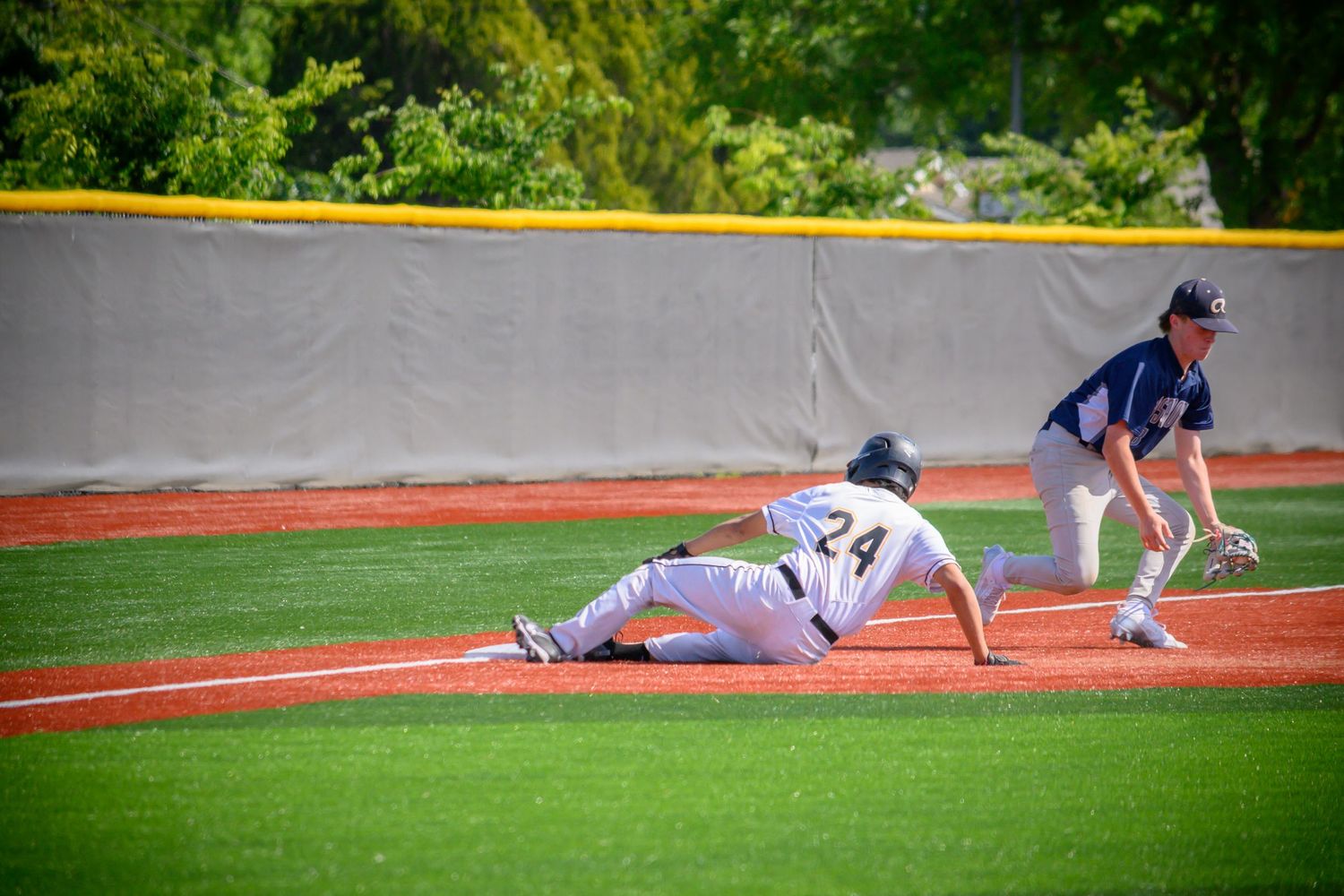 Baseball players compete in a close play at first base during game.
