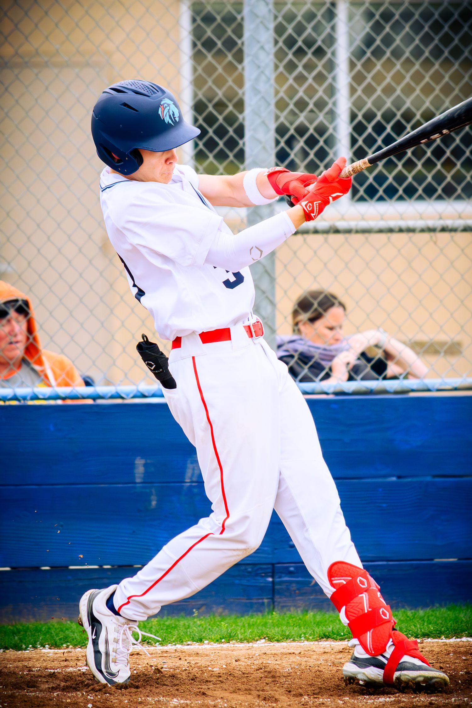 Baseball player in white uniform and red socks sliding into base during game.