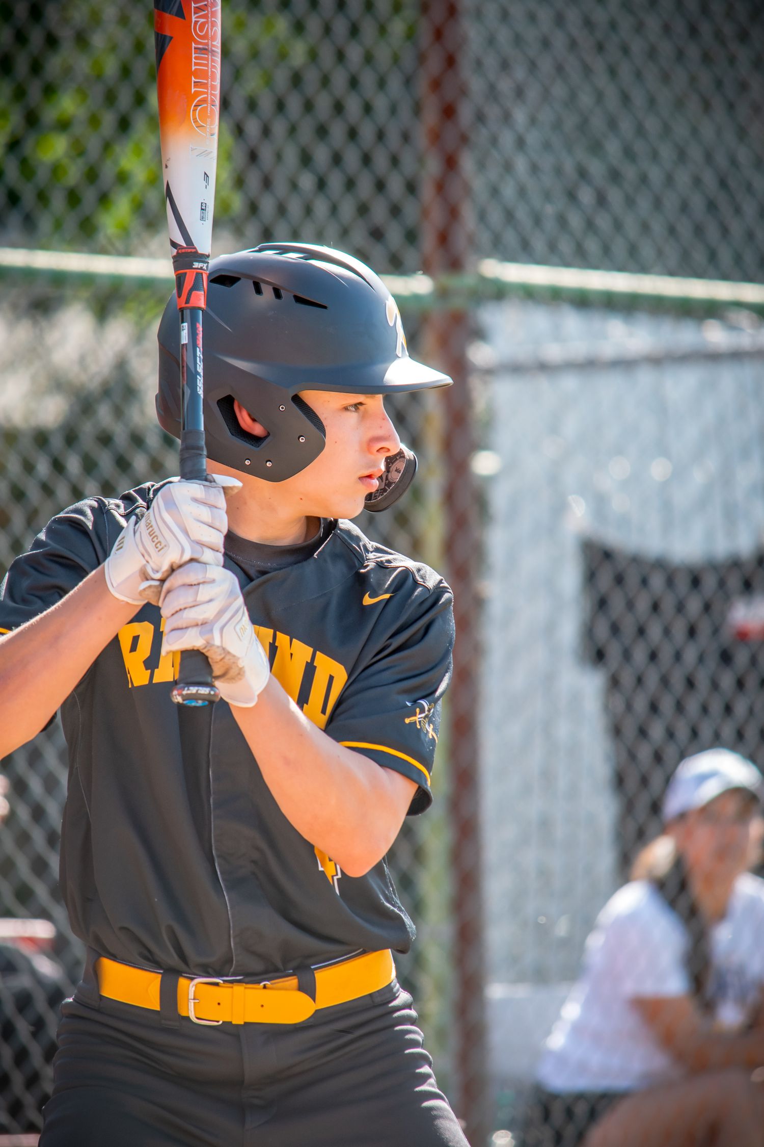 Baseball player in black and yellow uniform at bat in batting stance position.
