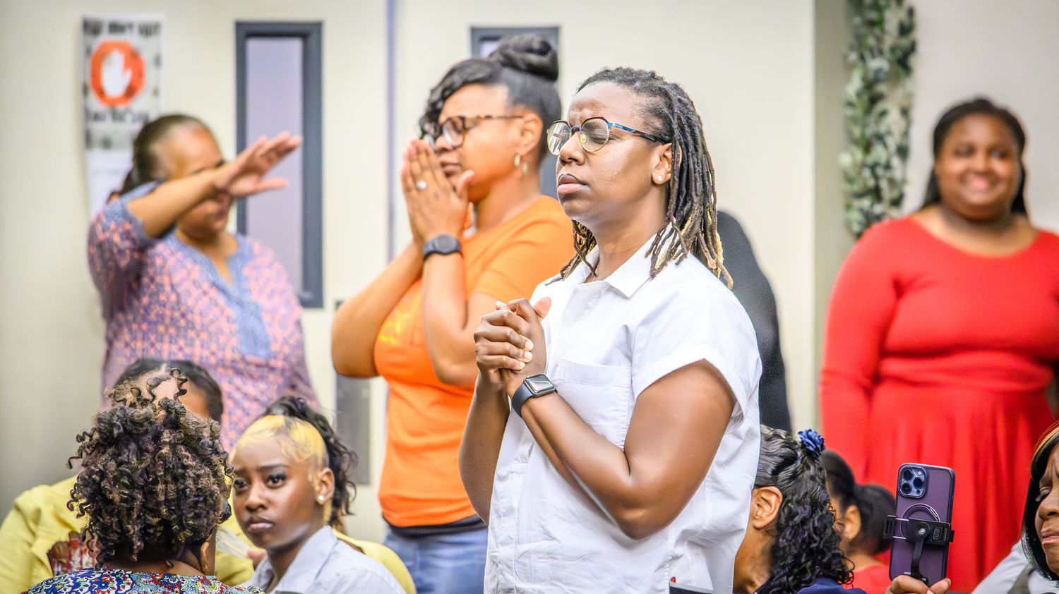 Church congregation members engaged in passionate worship with raised hands and expressive faces.