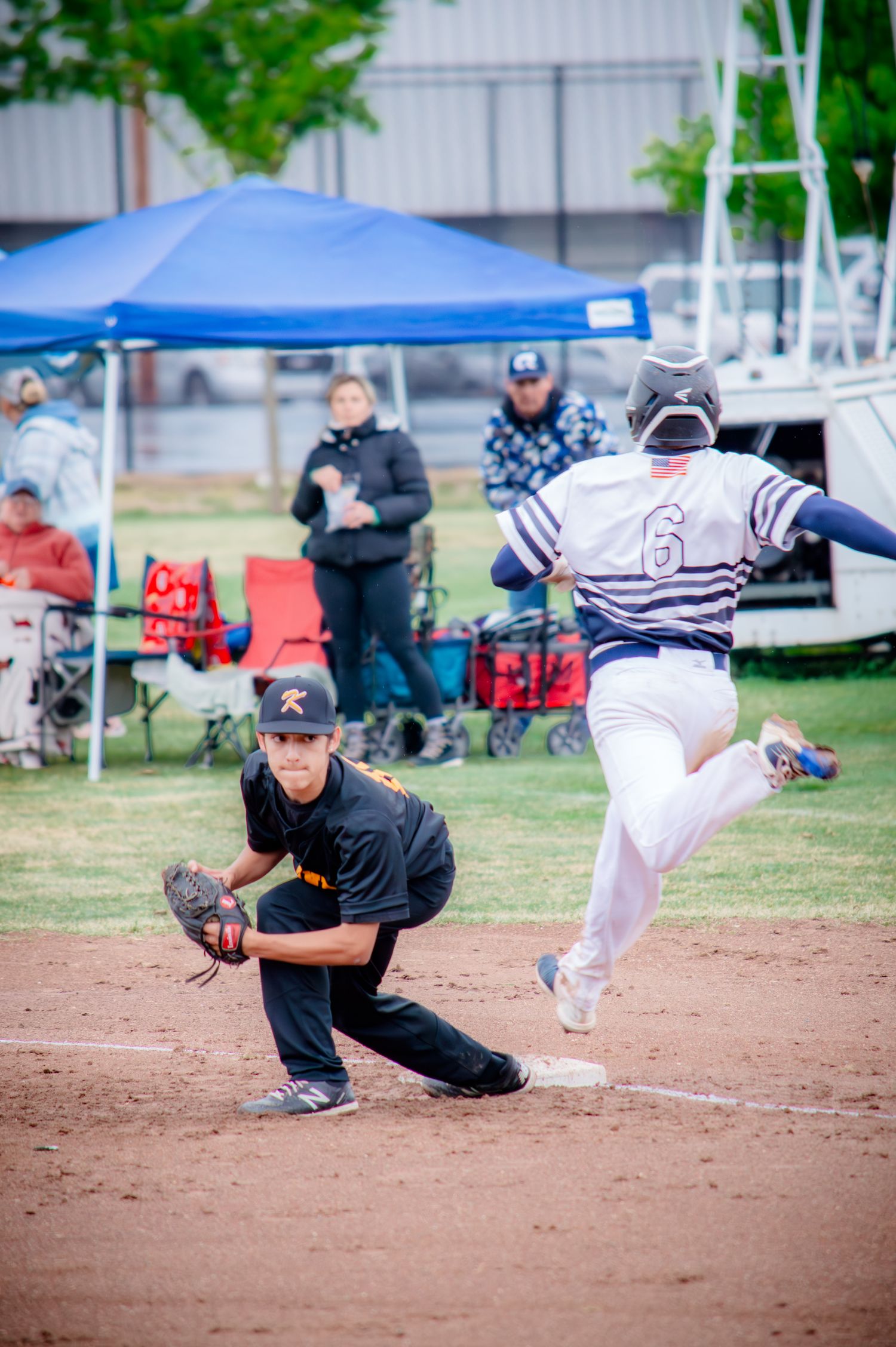 Baseball players in action during a sliding play at the base with spectators in background.