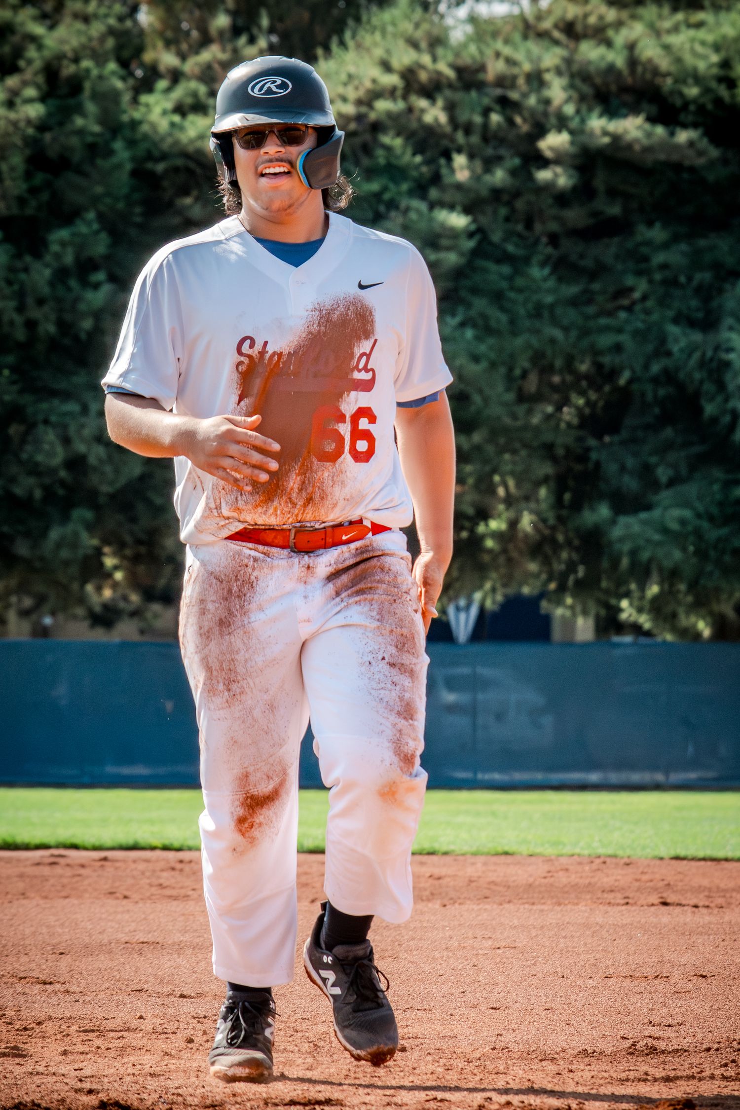 Baseball players in white uniforms covered in dirt while playing on a dusty infield during a game.