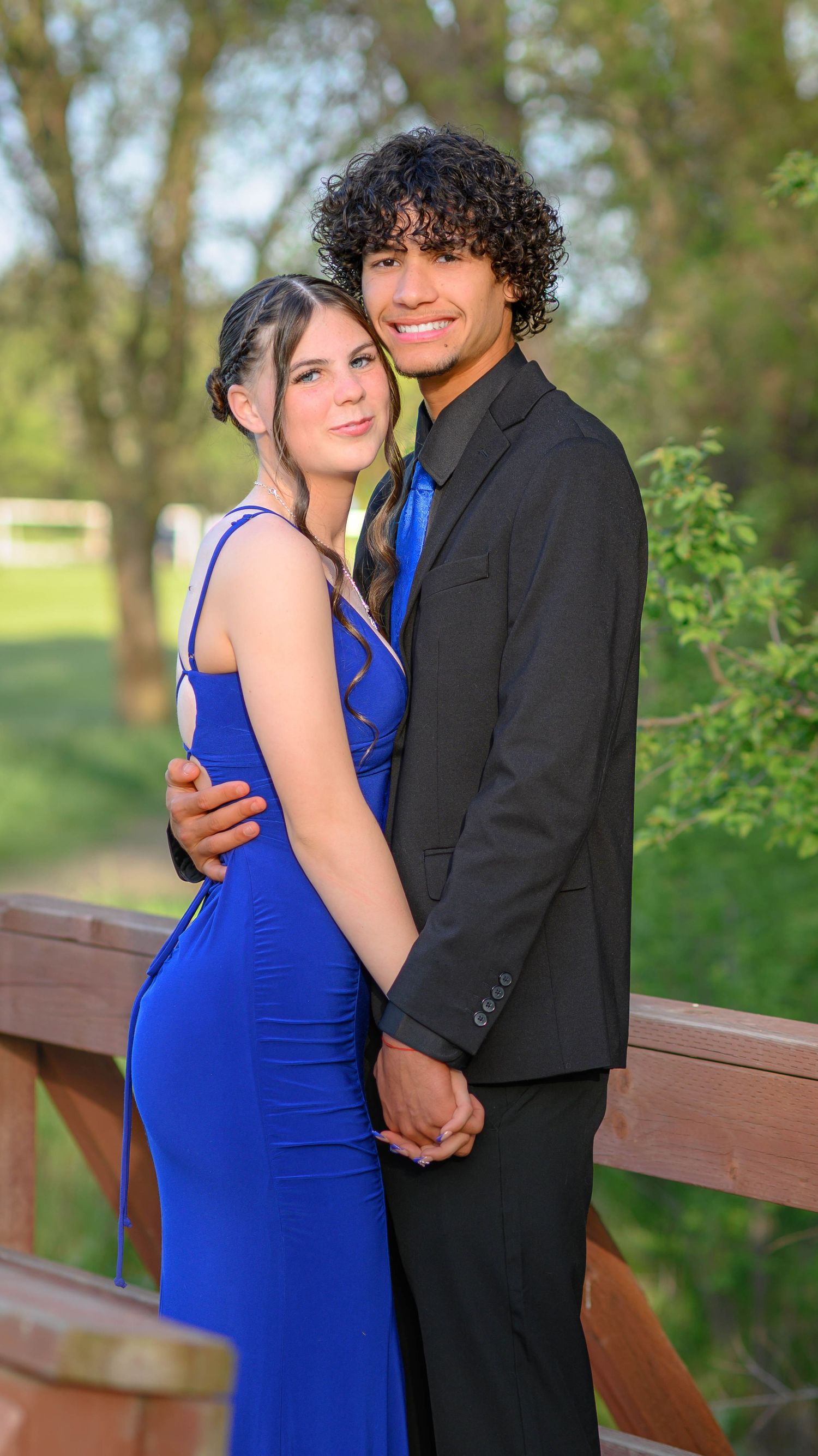 Couple in formal wear sharing intimate moment on wooden deck.
