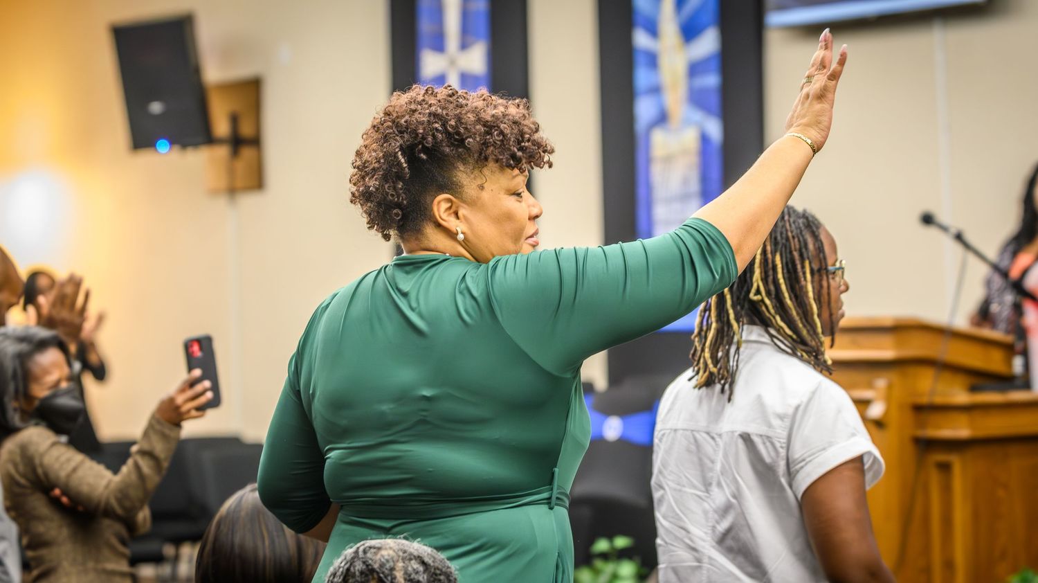 Worshipper raises hand during passionate church service moment.