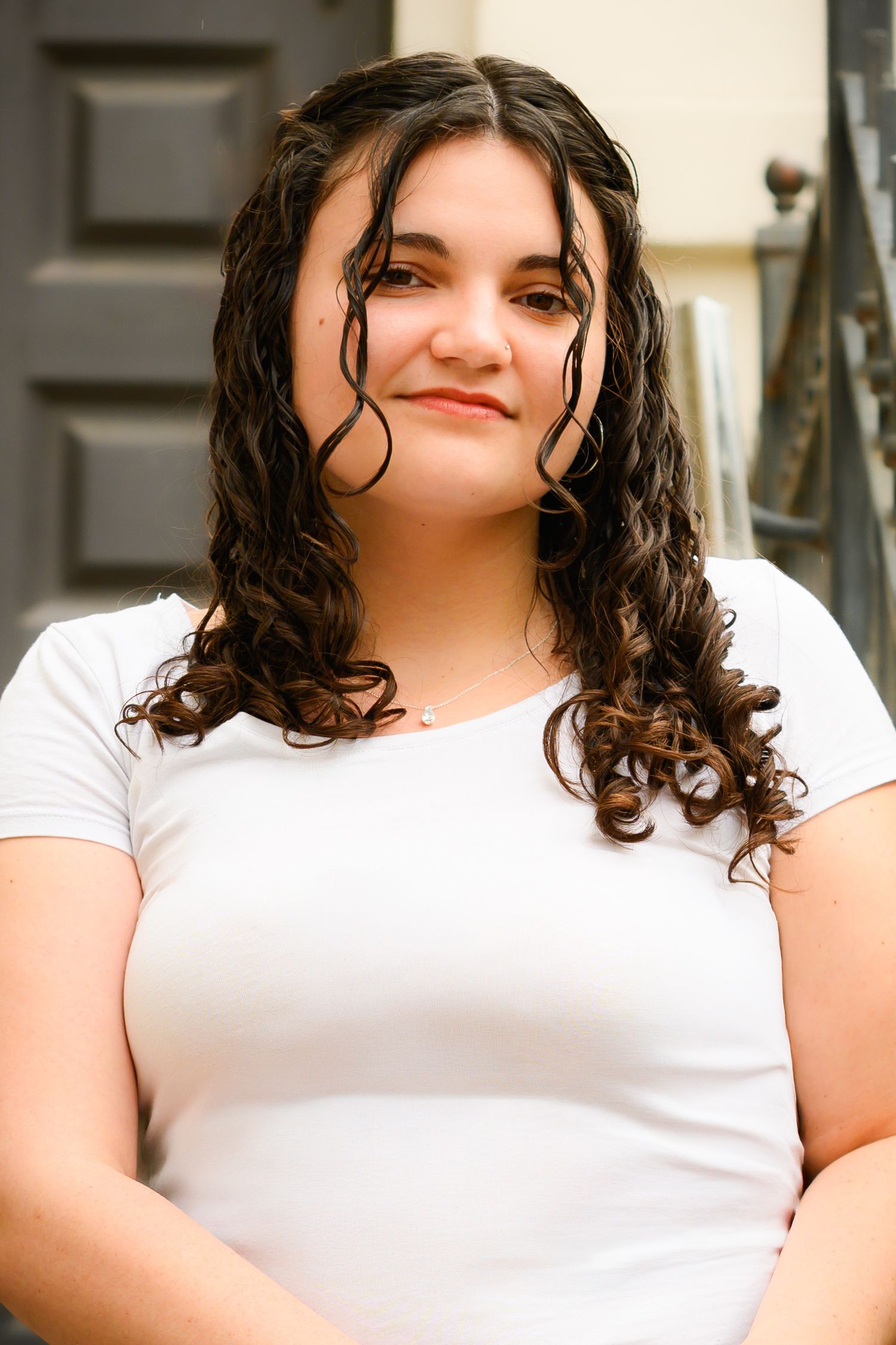Indoor portrait wearing simple white t-shirt with dark curly hair.