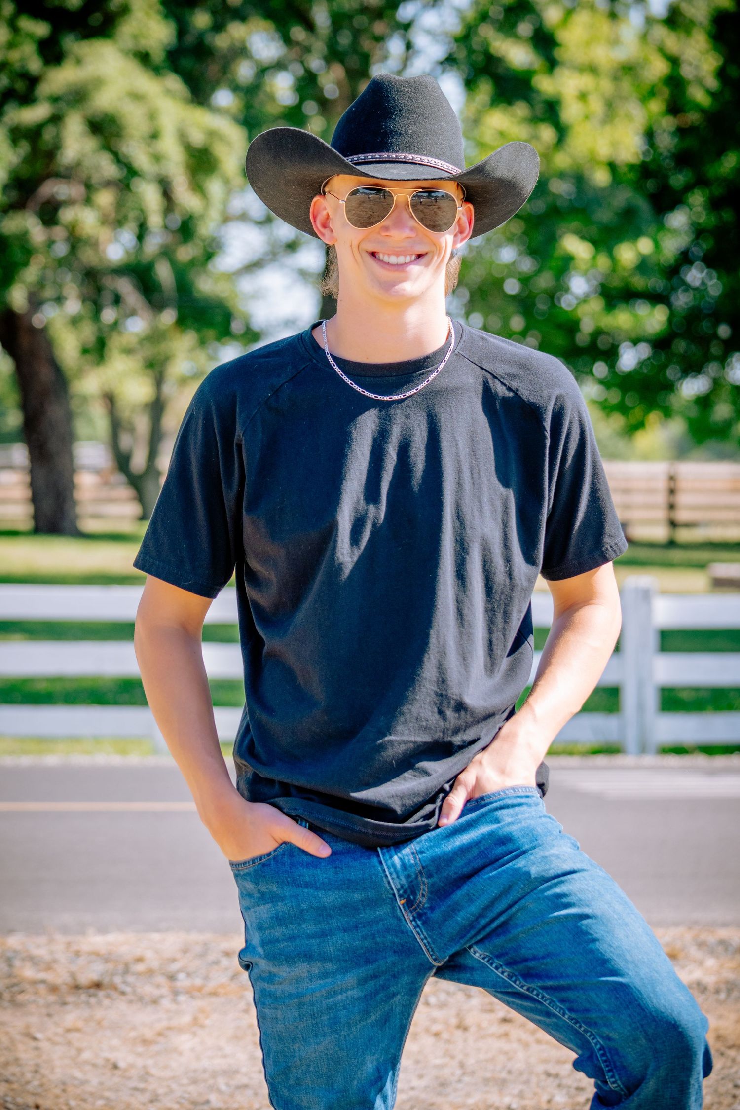 Casual country portrait session wearing black t-shirt, jeans and cowboy hat outdoors.