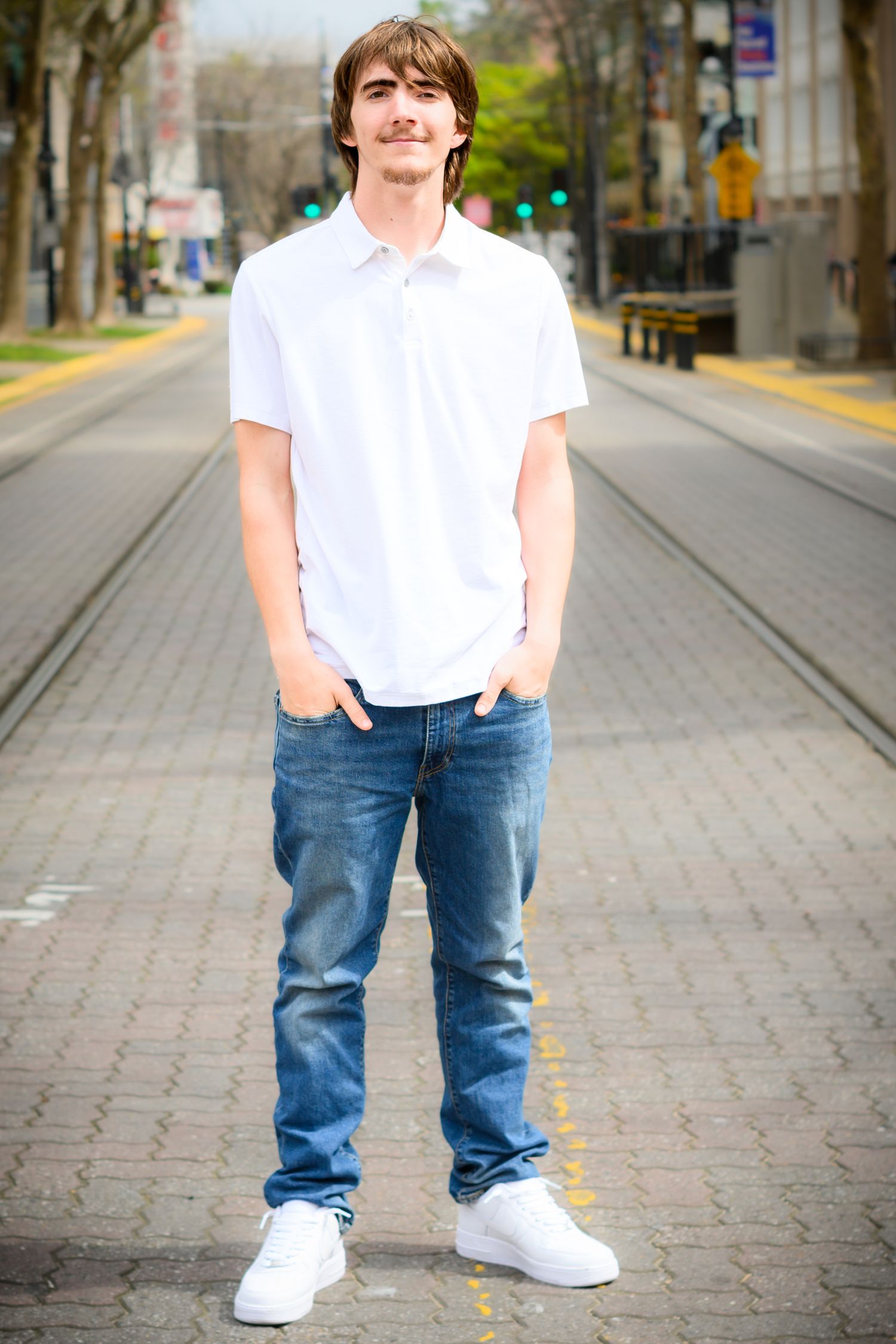 Street portrait on brick walkway wearing white polo and jeans.