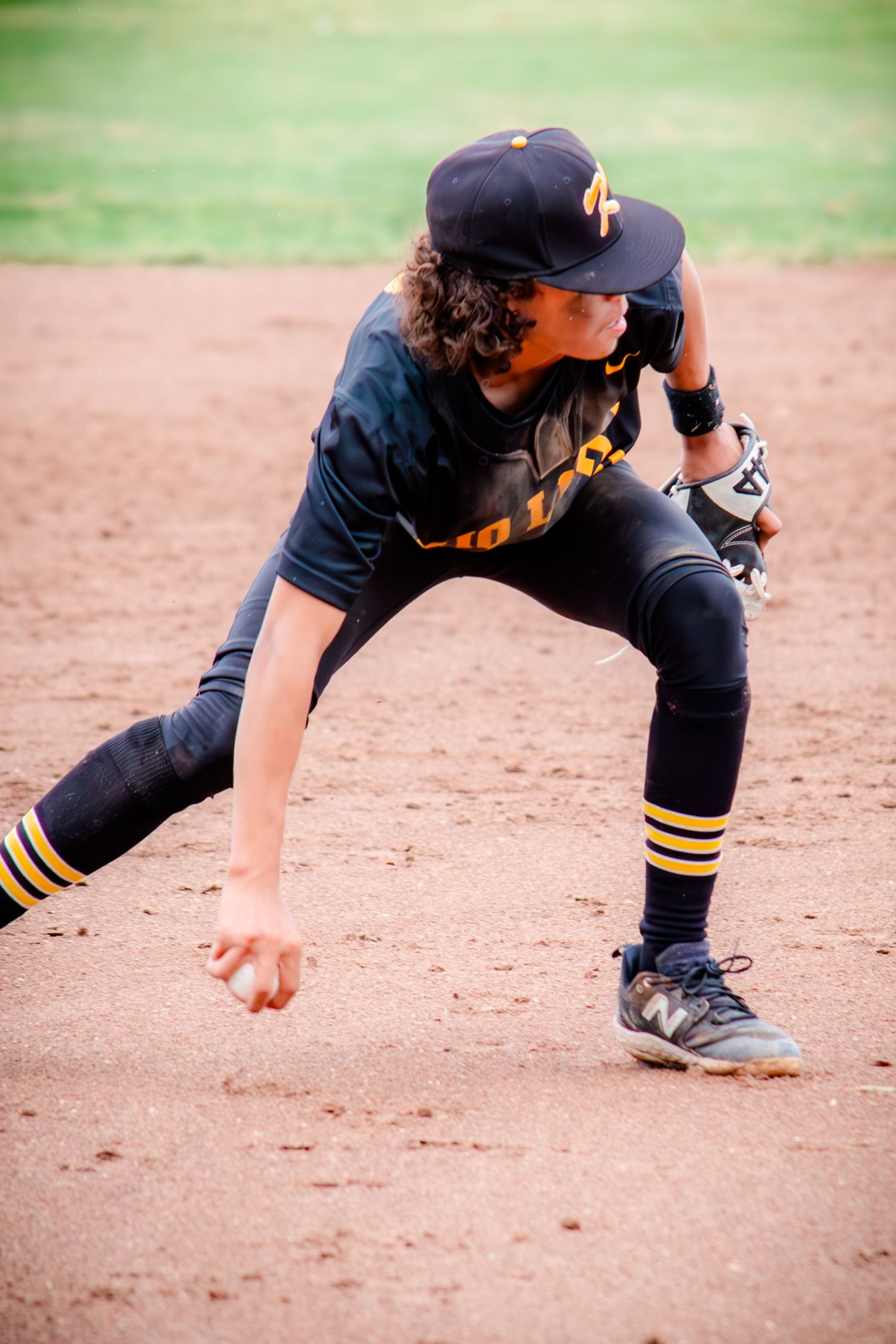 Baseball player in black uniform demonstrating fielding stance sequence on dirt infield.