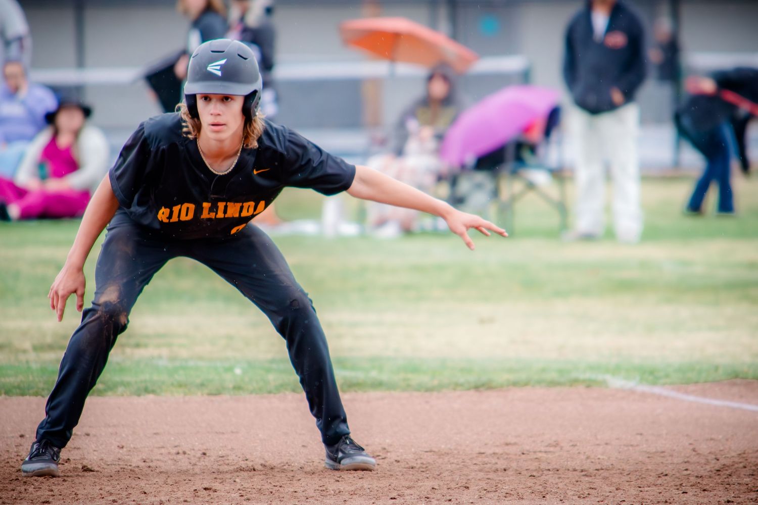 Baseball player in dark uniform positioned defensively on infield dirt.