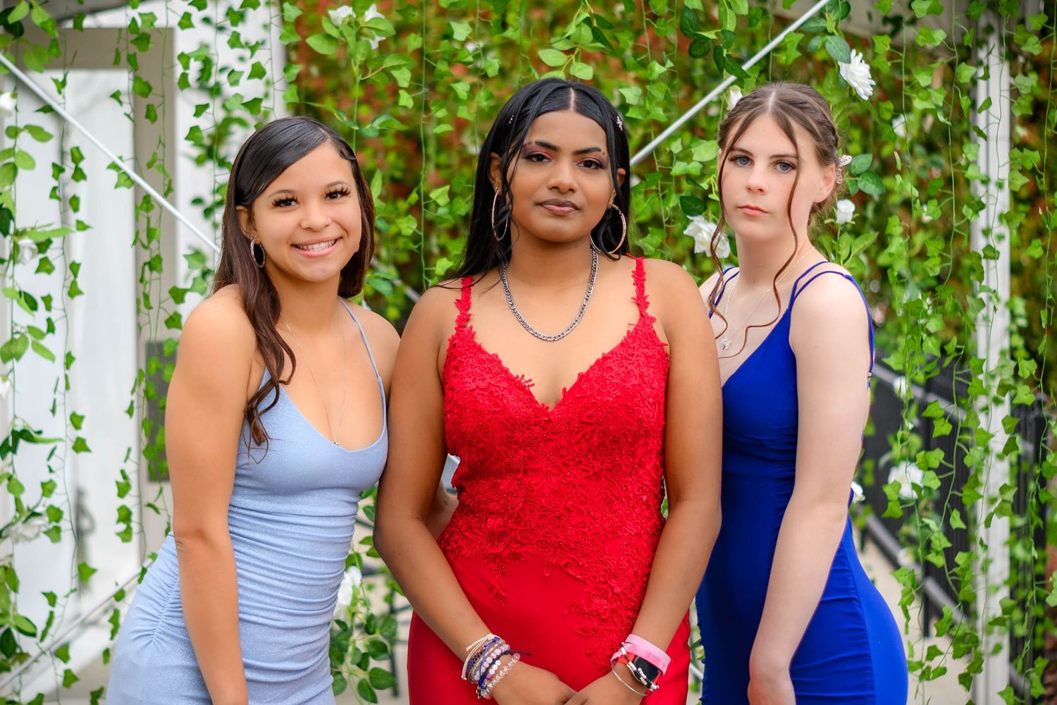 Group photo showing people in formal dresses against green garden backdrop.