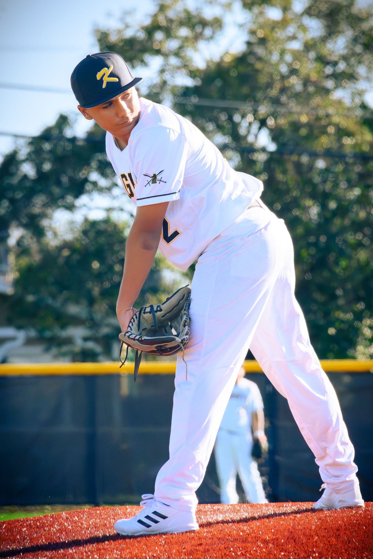 Baseball player fielding position with glove extended on red turf training field during practice.