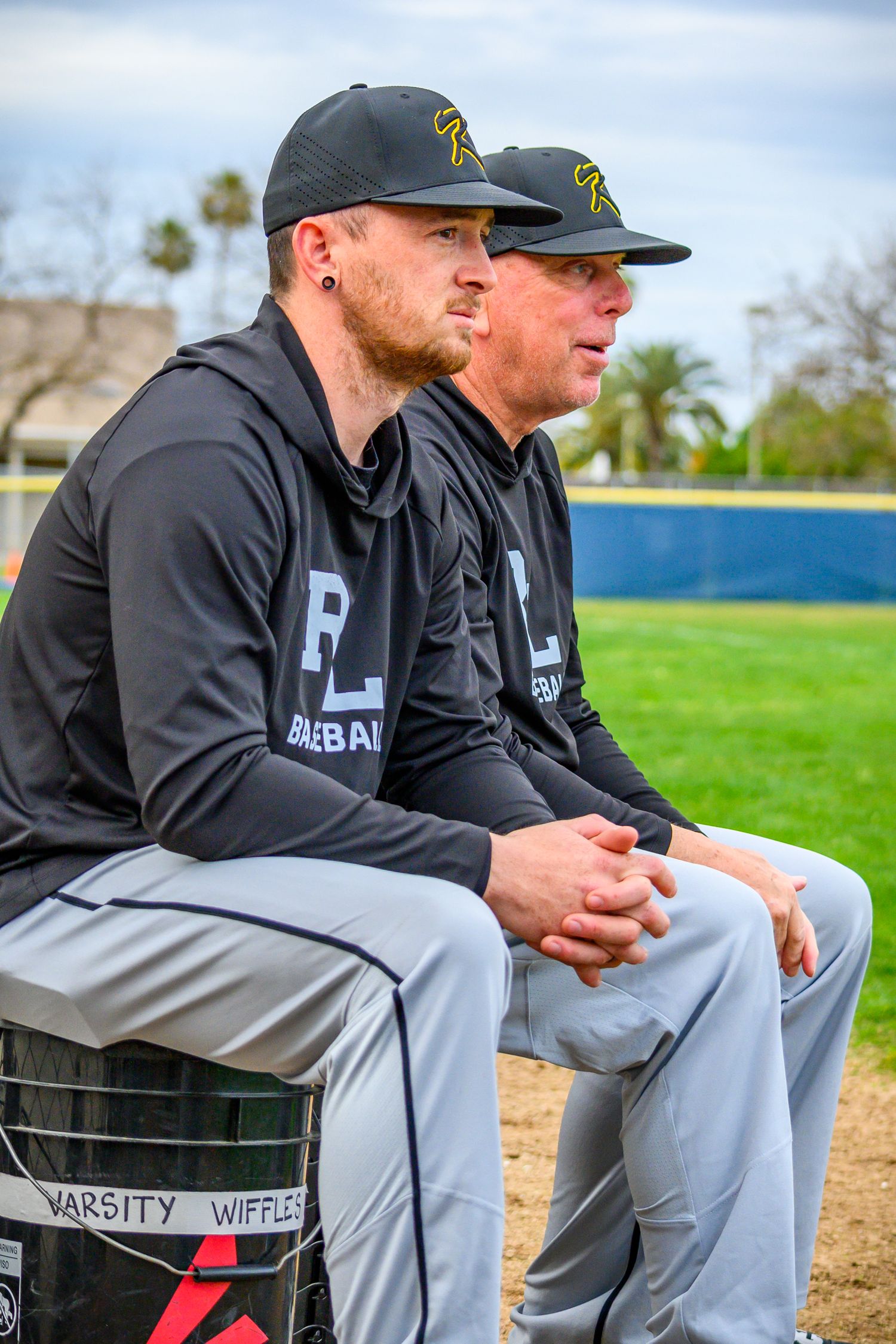 Baseball coaches watch from dugout during game.