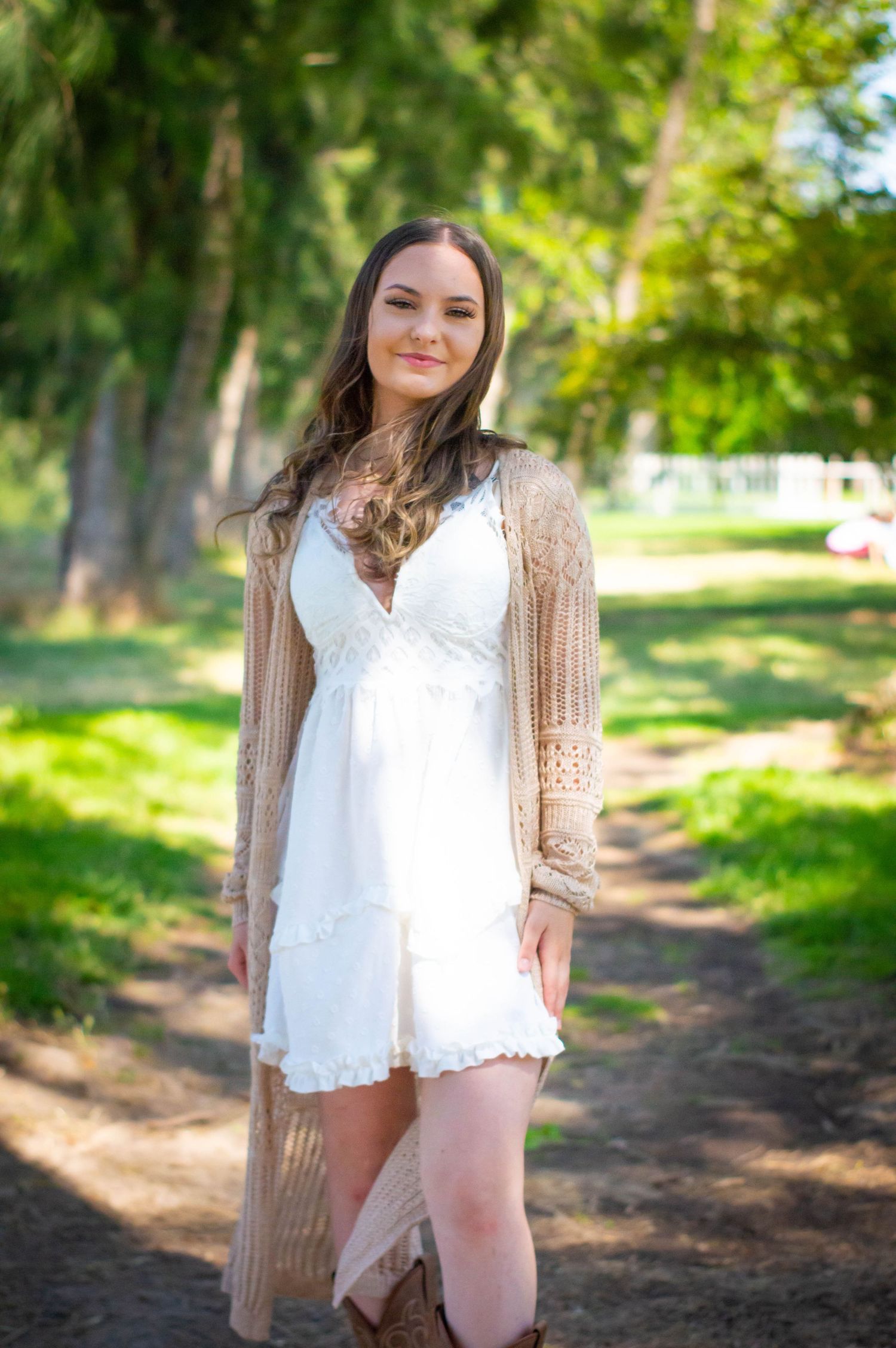 Spring portrait in a wooded area wearing white lace top and beige cardigan.
