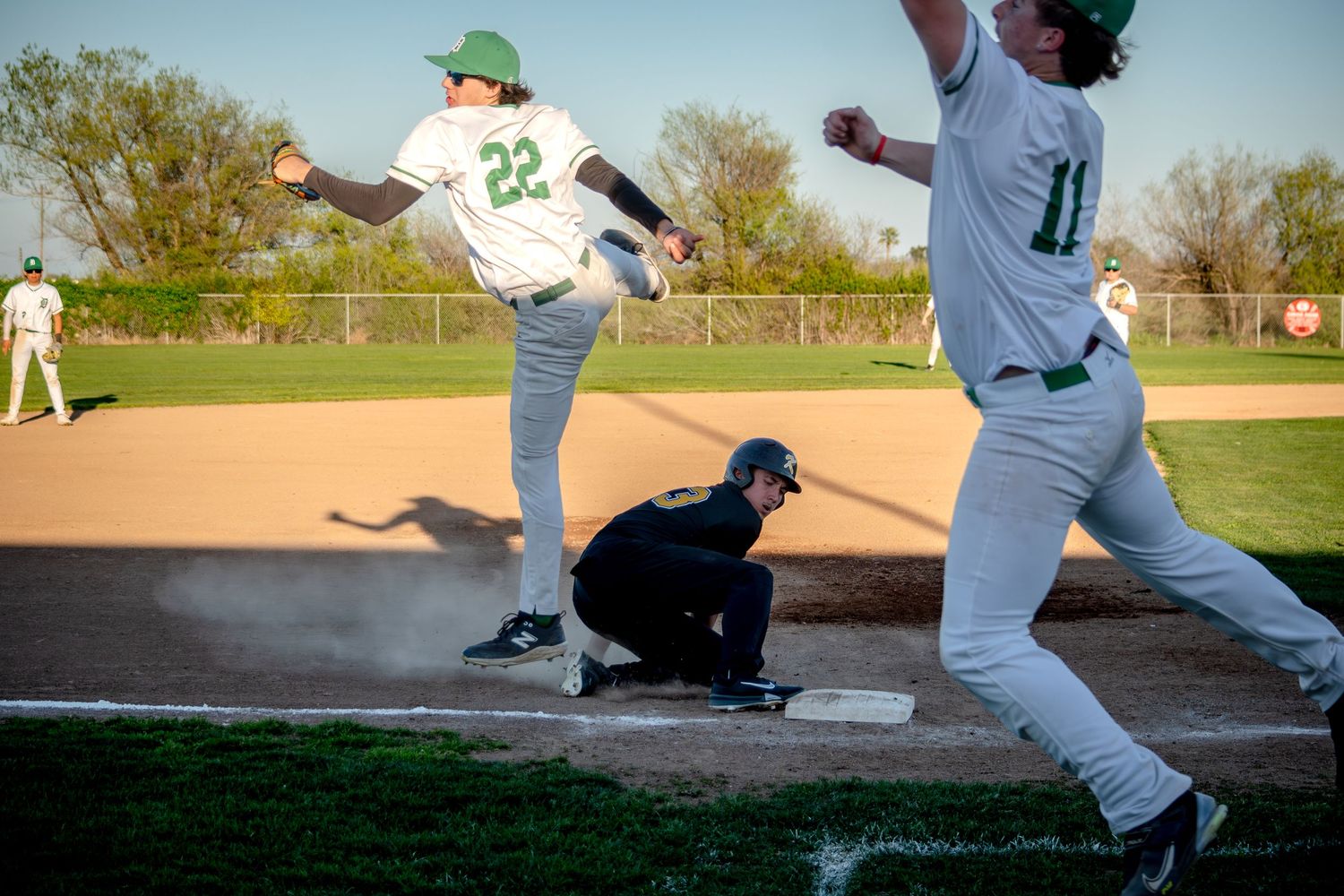 Baseball players demonstrate pitching and fielding techniques on a sunny day at a baseball diamond.