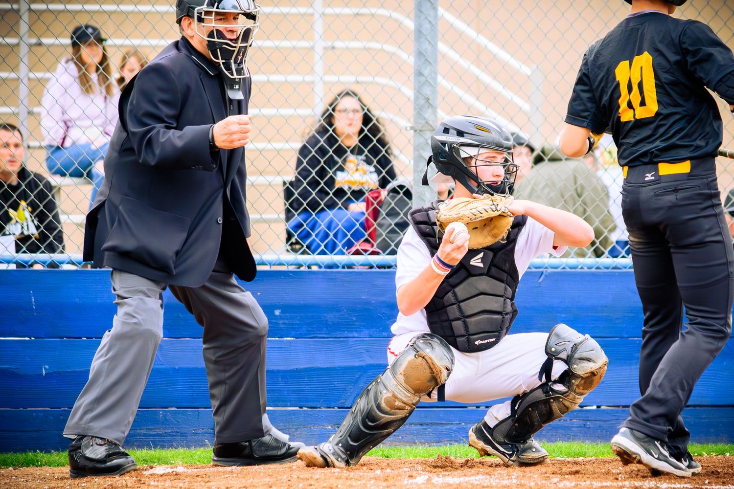 Baseball players crouch in position behind home plate during a game.