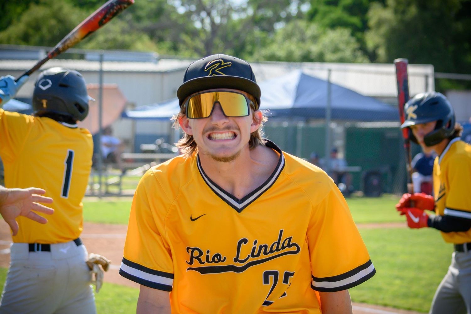 Baseball player in yellow Rio Linda jersey smiles on baseball field.