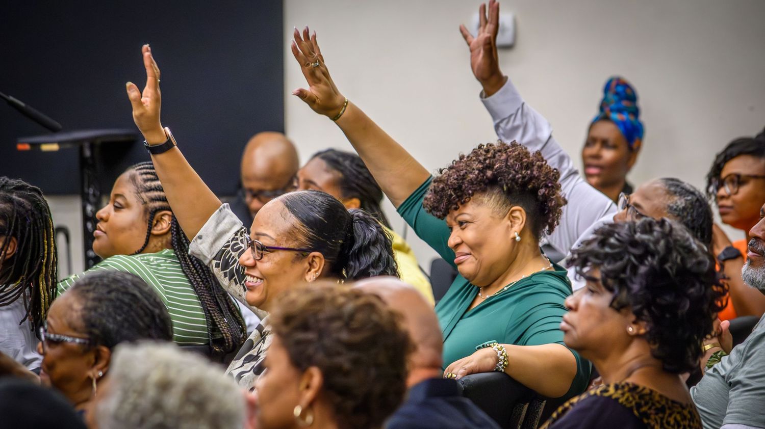 Enthusiastic church congregation members raising hands in worship during a spirited service.