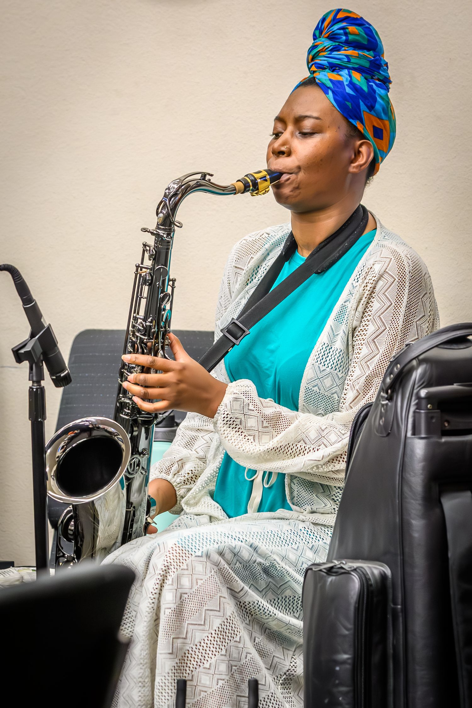 Musician in turban and white lace plays saxophone during performance.