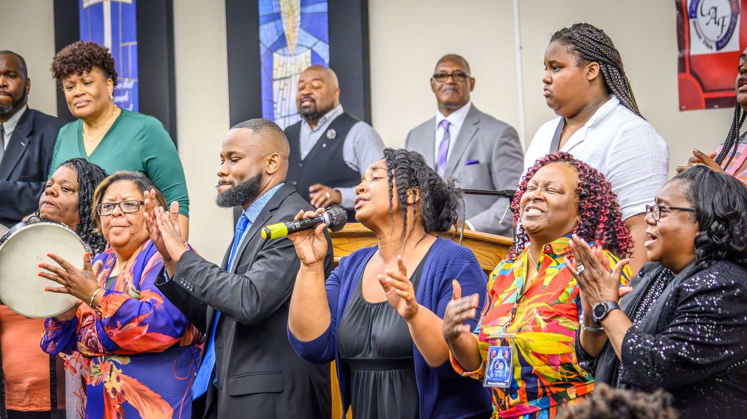 Large group of worshippers with raised hands during an energetic church service.
