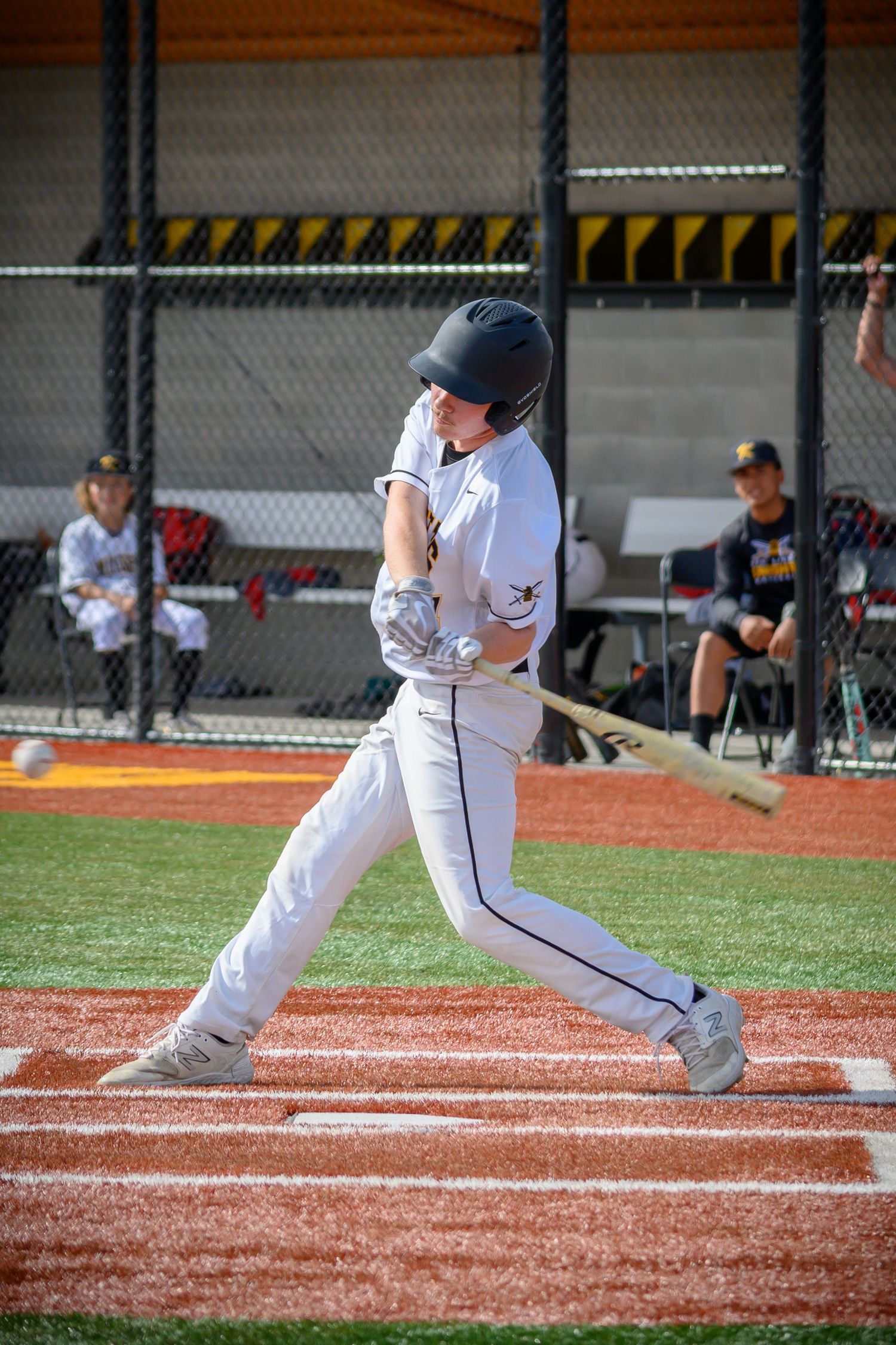 Baseball batter in white uniform demonstrating proper batting stance at home plate.