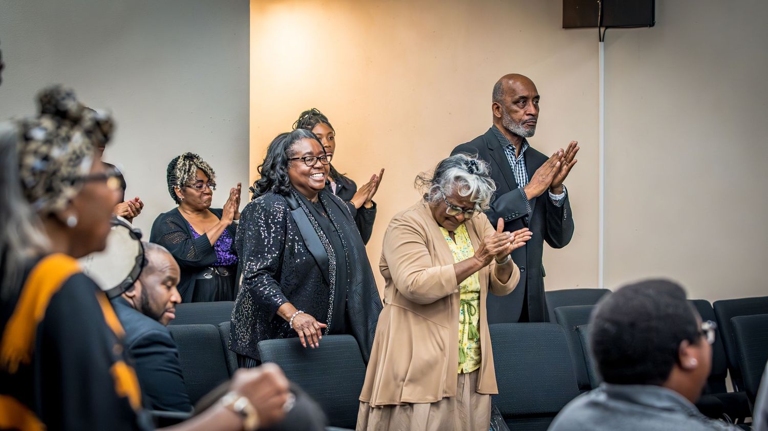 People applaud and raise their hands at a church or community gathering.