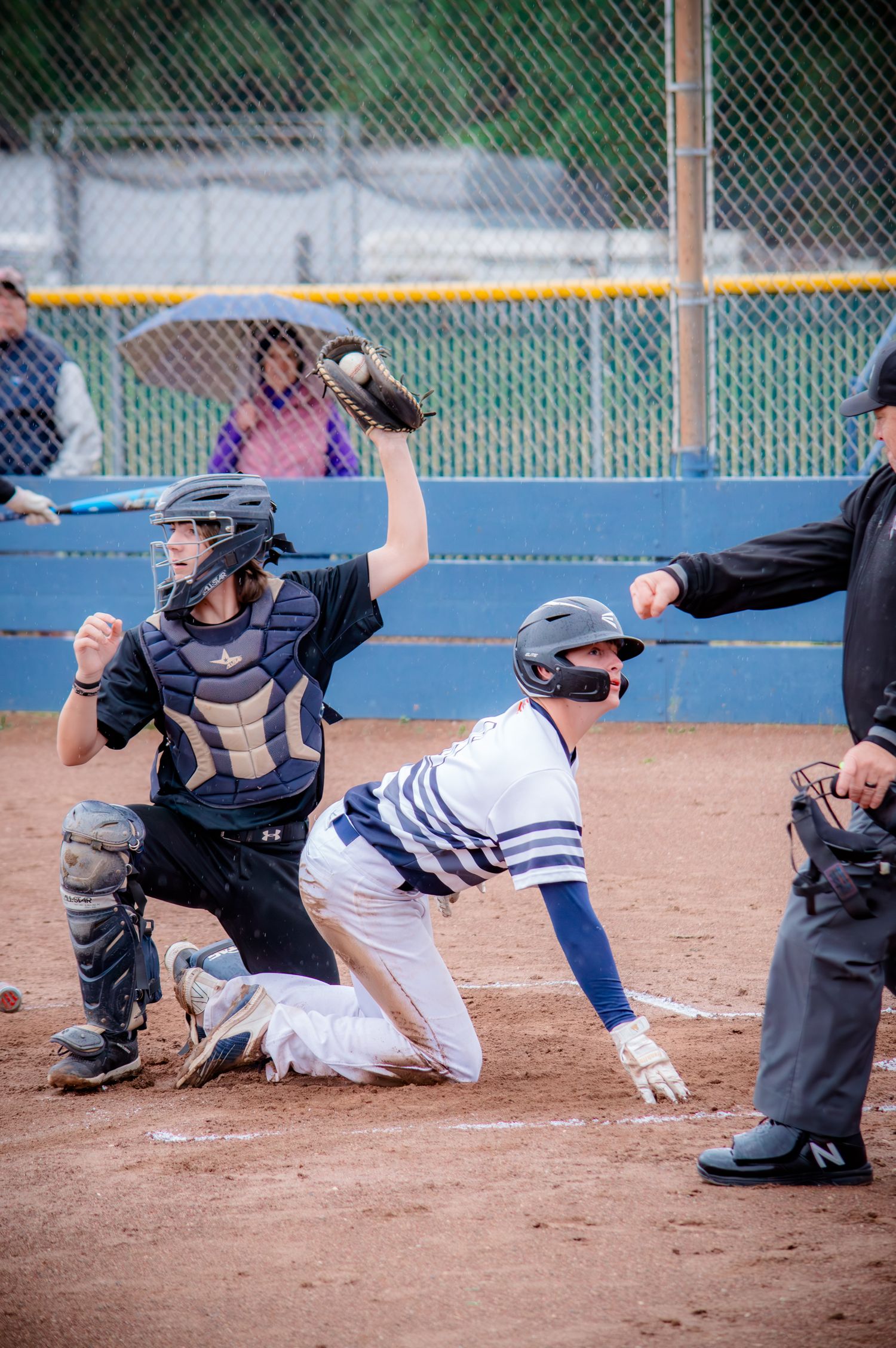Baseball player sliding dramatically into base during game with umpire watching.
