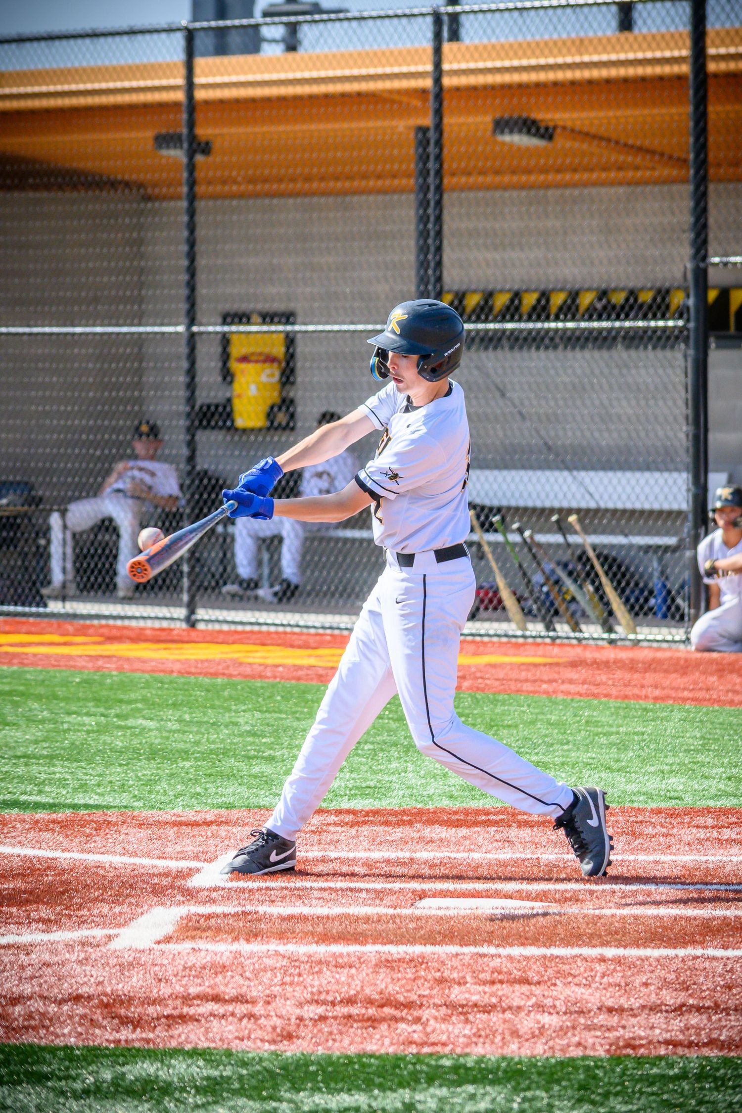 Baseball batter in white uniform swings bat at home plate during game.